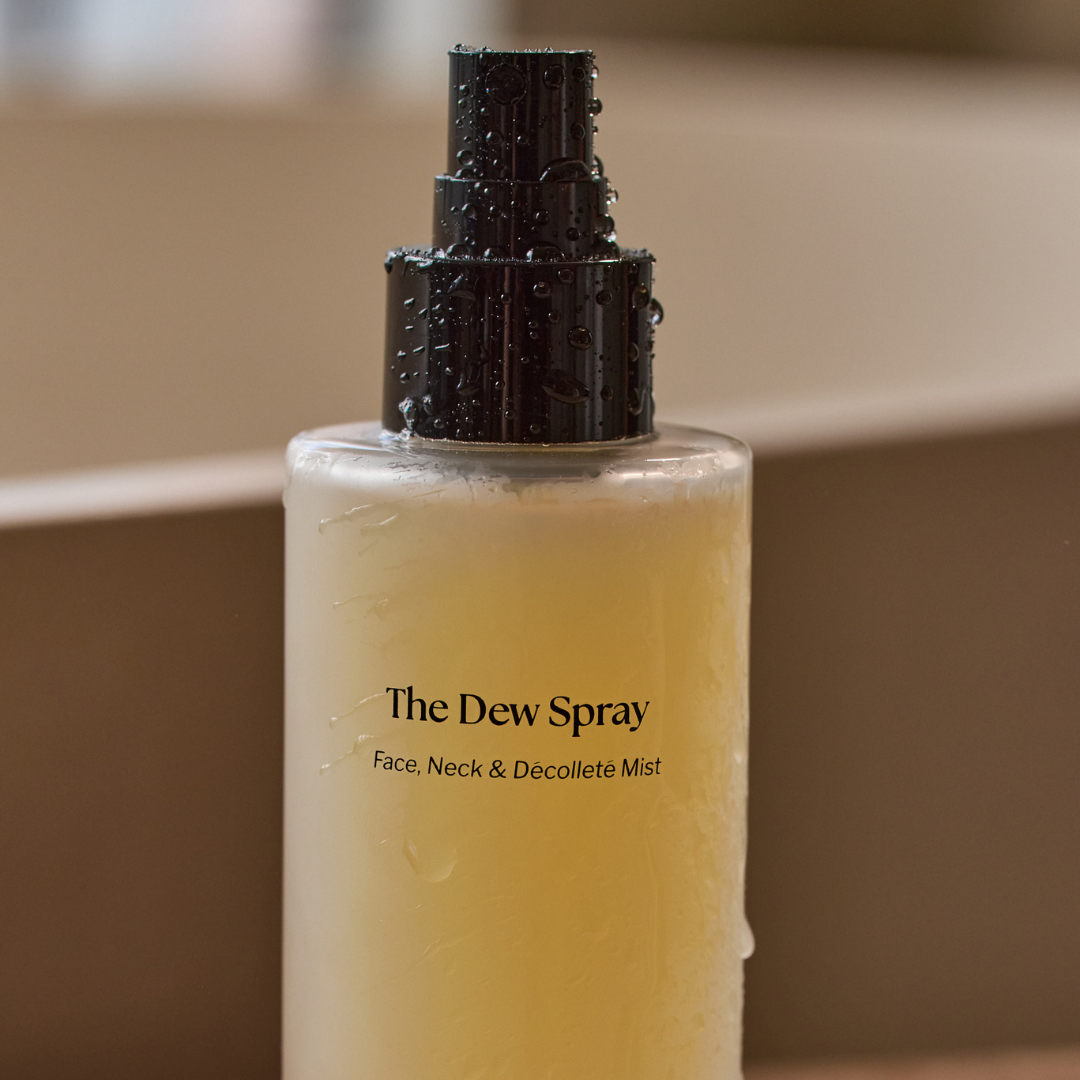 Bottle of 'The Dew Spray' with a black pump on a beige background