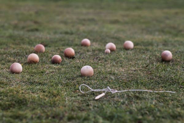 Golf balls scattered on a grassy field with a string