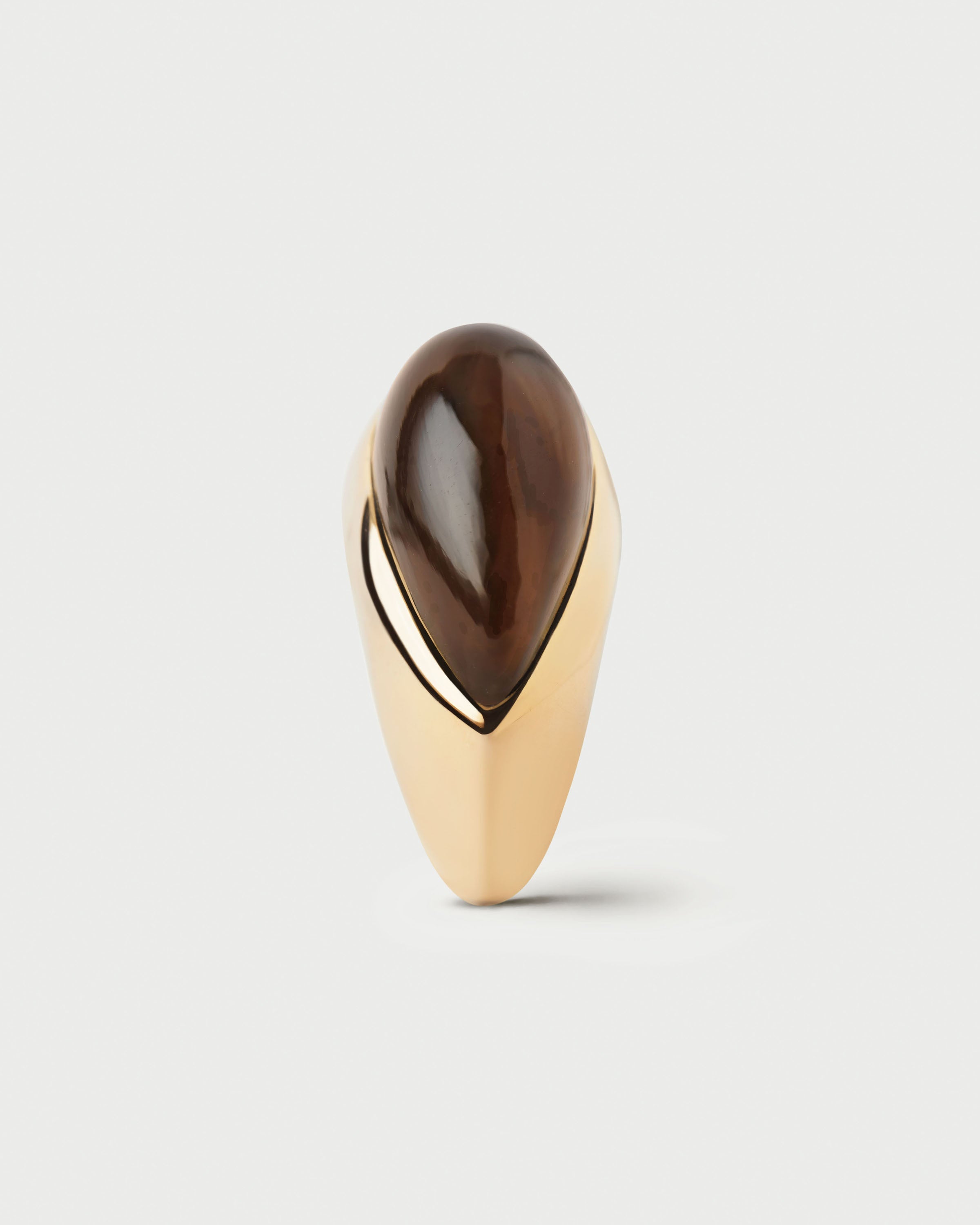 Gold ring with a large brown stone on a light gray background