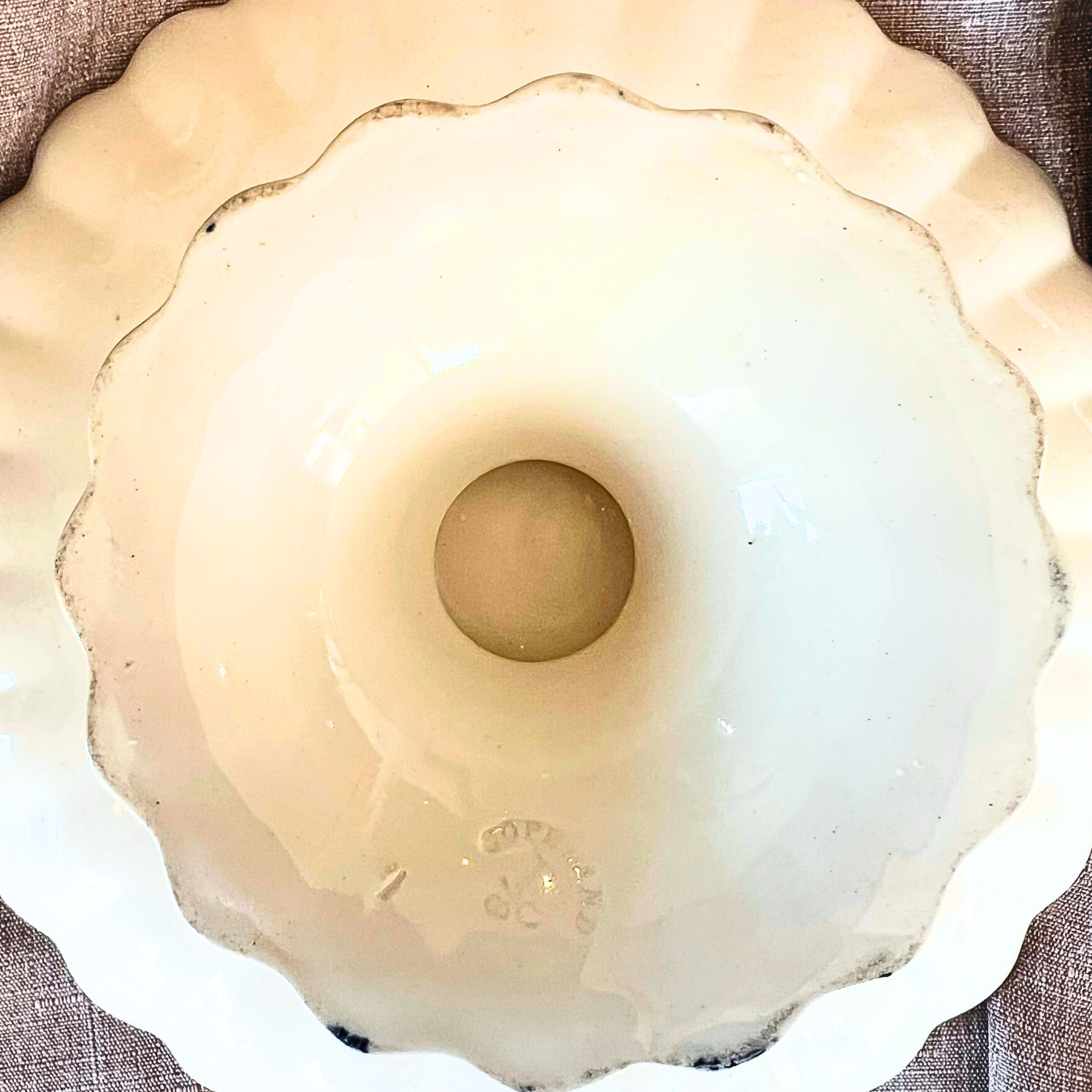 Close-up of a white ceramic bowl with a scalloped edge on a textured surface.