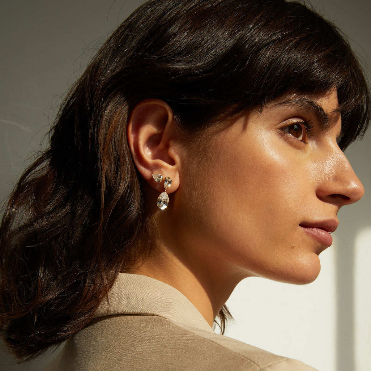 Close-up of a woman wearing earrings with a neutral background