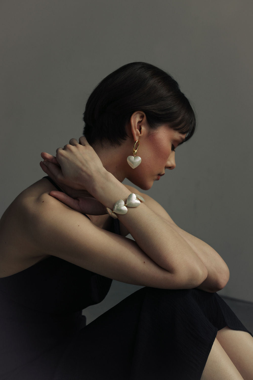 Woman wearing heart-shaped earrings against a neutral background