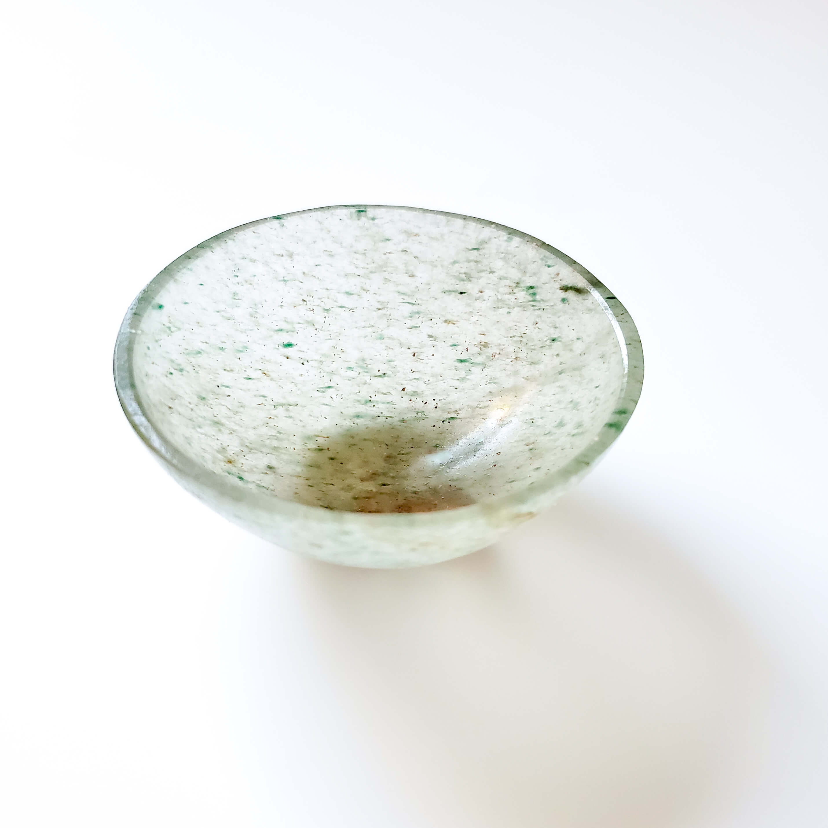 Round glass bowl with speckled pattern on a white background