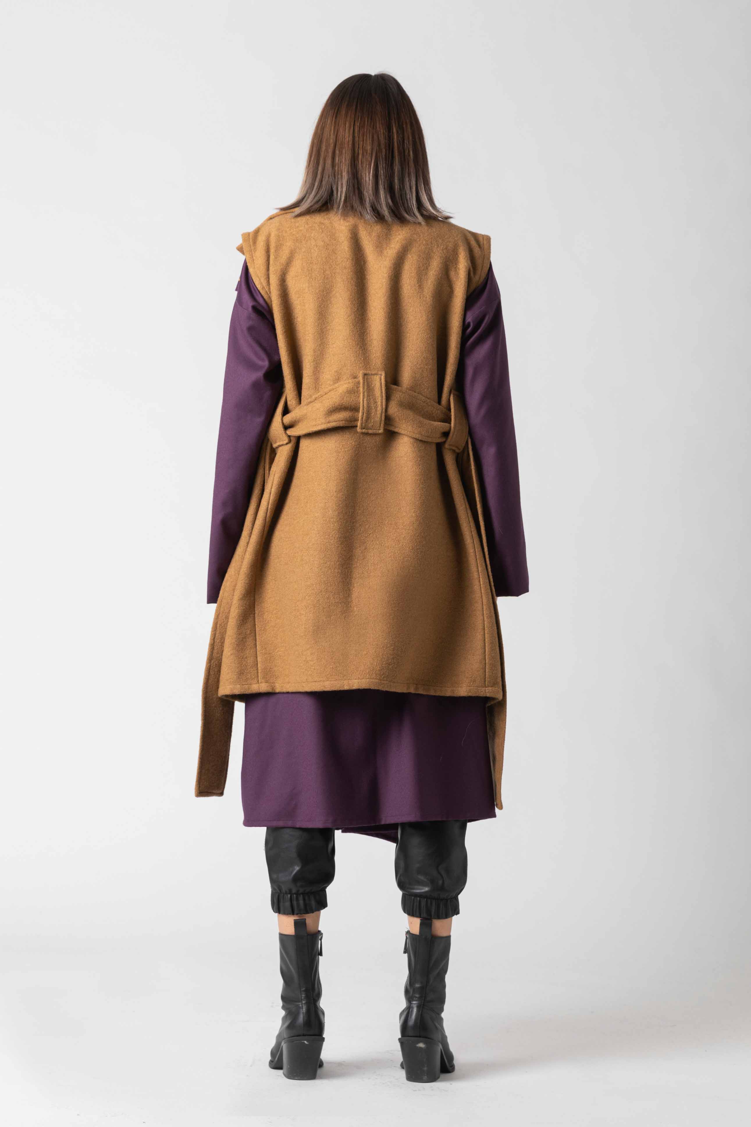 Person wearing a long brown coat with purple sleeves and a matching skirt on a white background