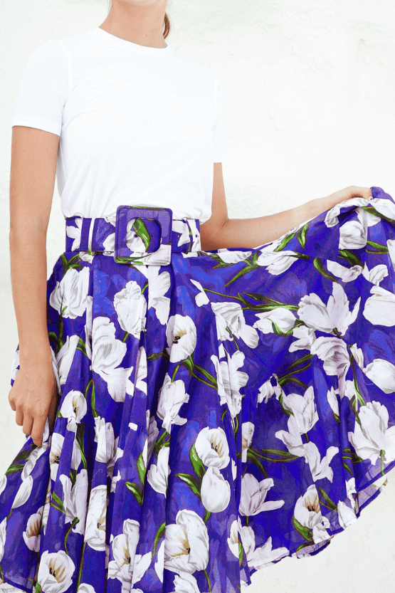 Woman wearing a white top and a blue floral skirt on a white background