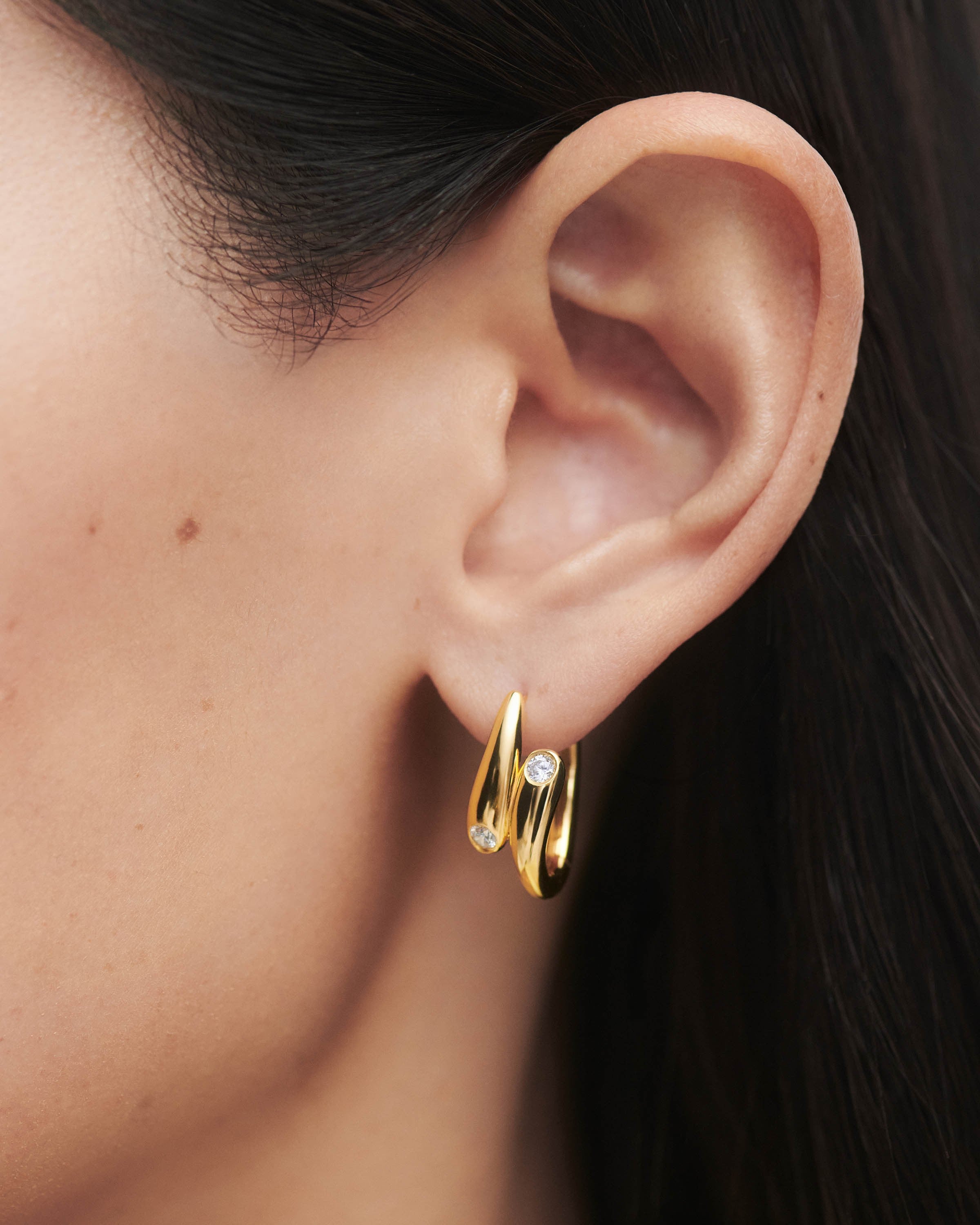 Gold hoop earring with a diamond on an ear