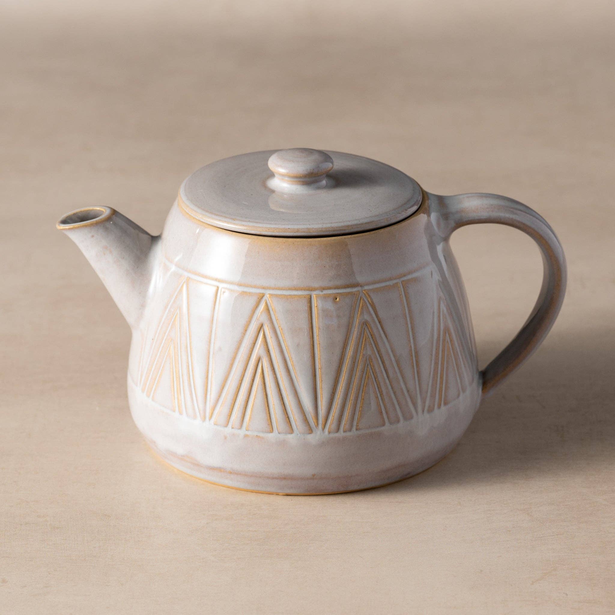 Ceramic teapot with geometric design on a beige background
