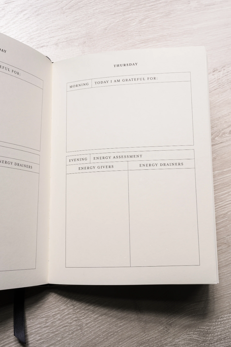 Open notebook with a daily reflection page on a wooden surface