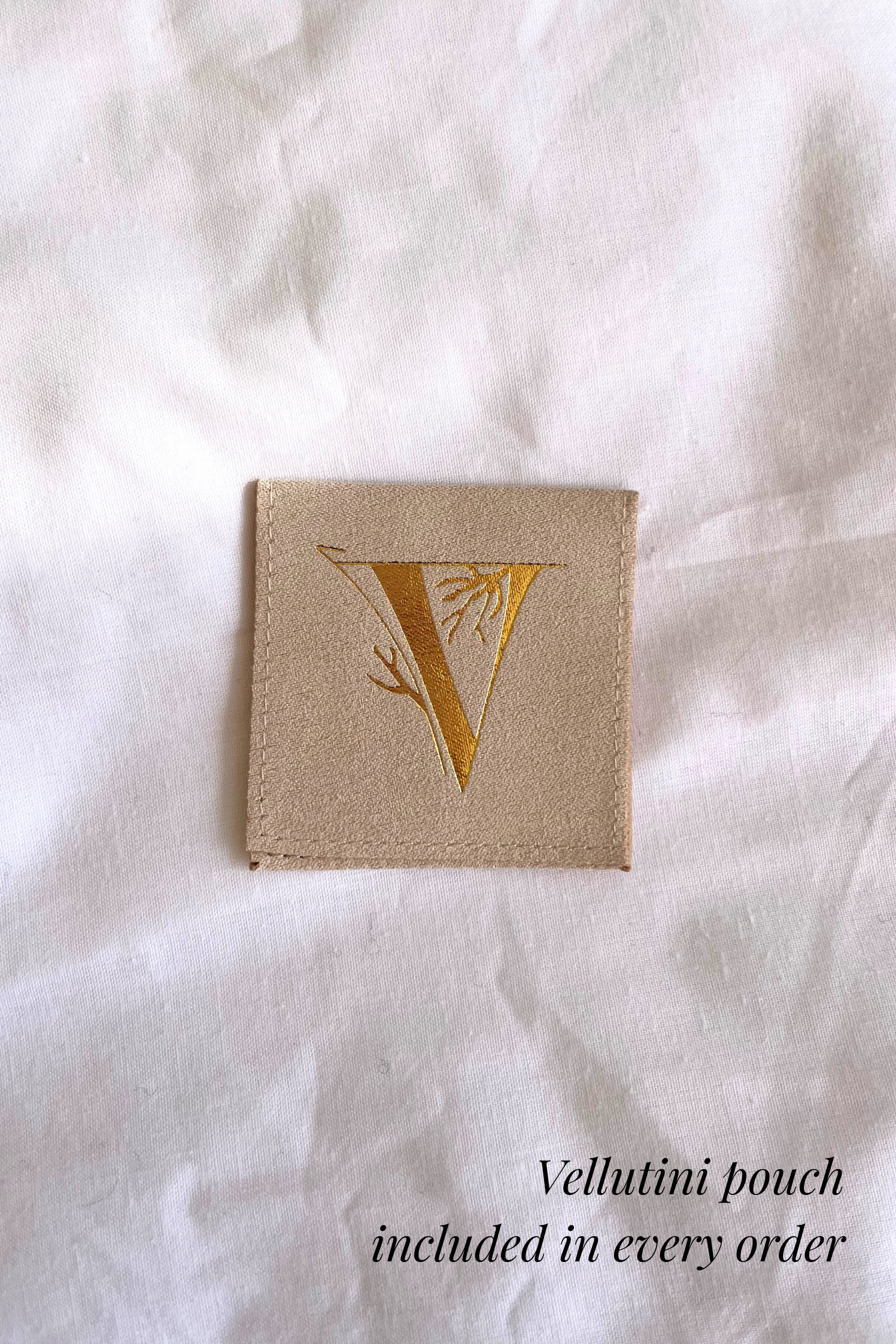 Tan colored Vellutini jewelry pouch on a white silk background