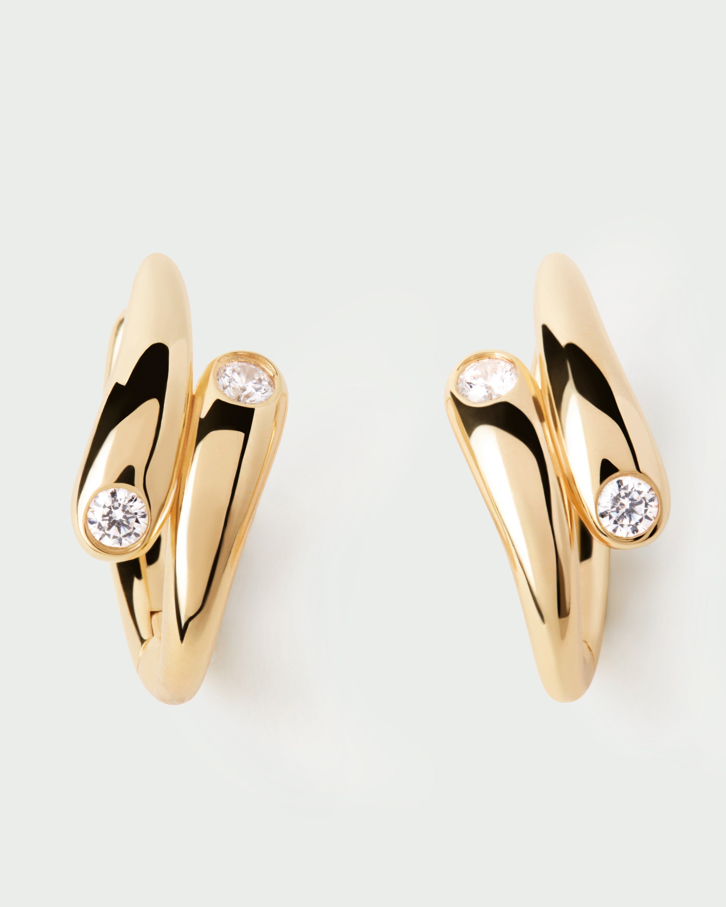 Gold earrings with diamond accents on a light gray background