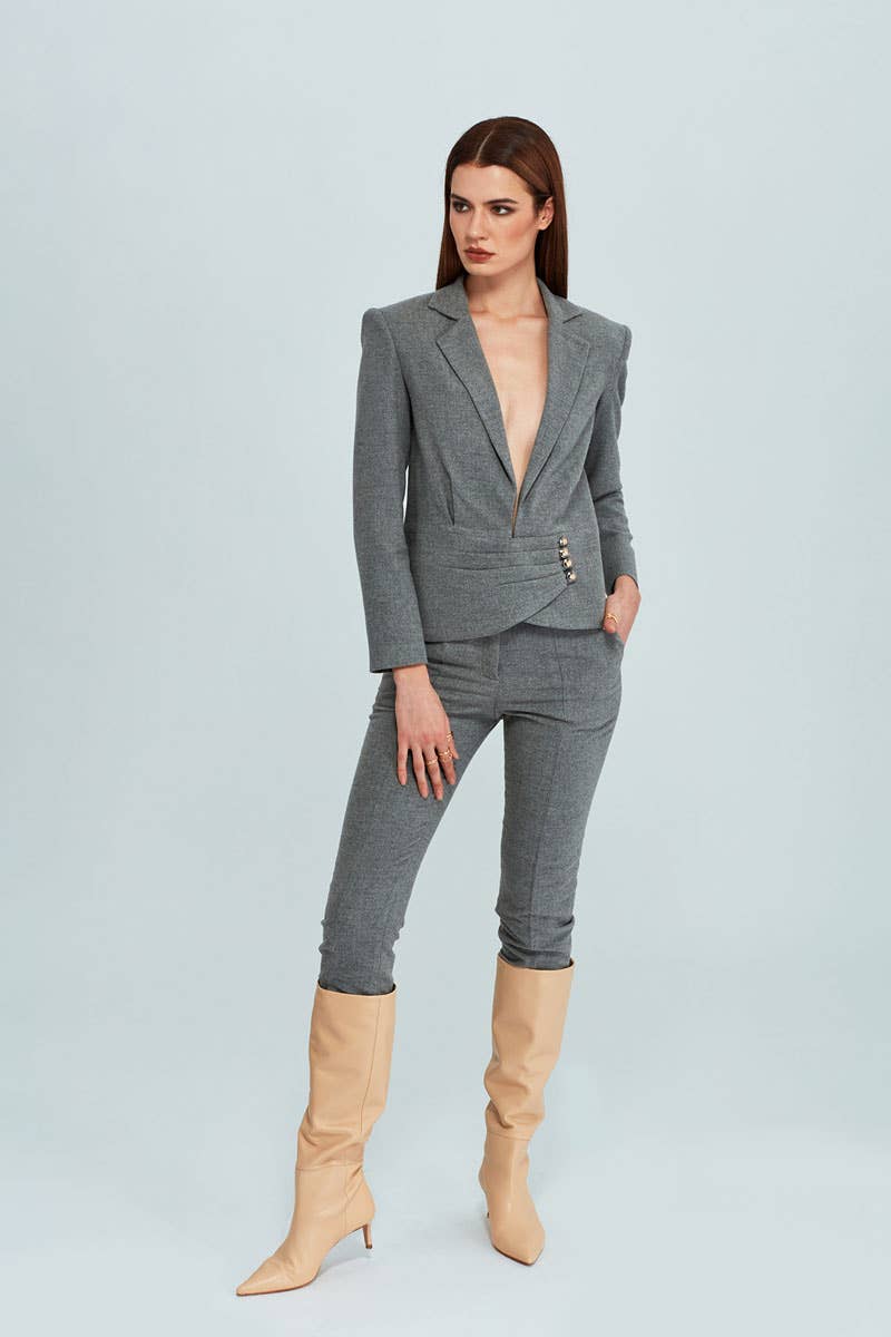 Woman wearing a gray suit with beige boots on a light blue background
