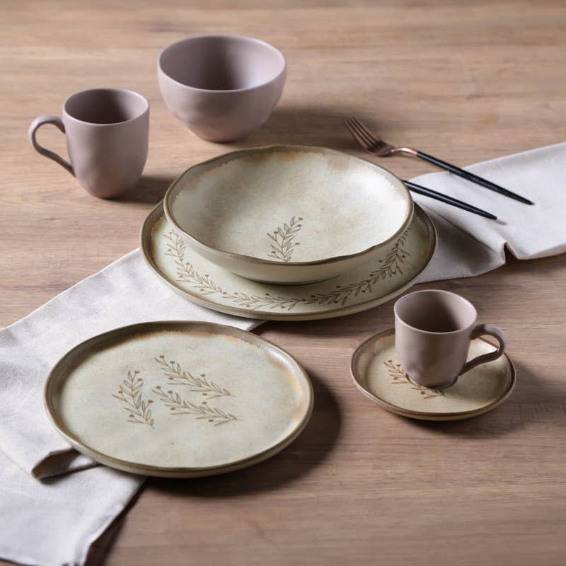 Ceramic dinnerware set with plates, bowls, and mugs on a wooden table.
