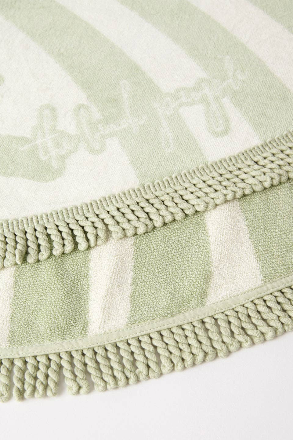 Green and white striped towel with braided edge on a white background
