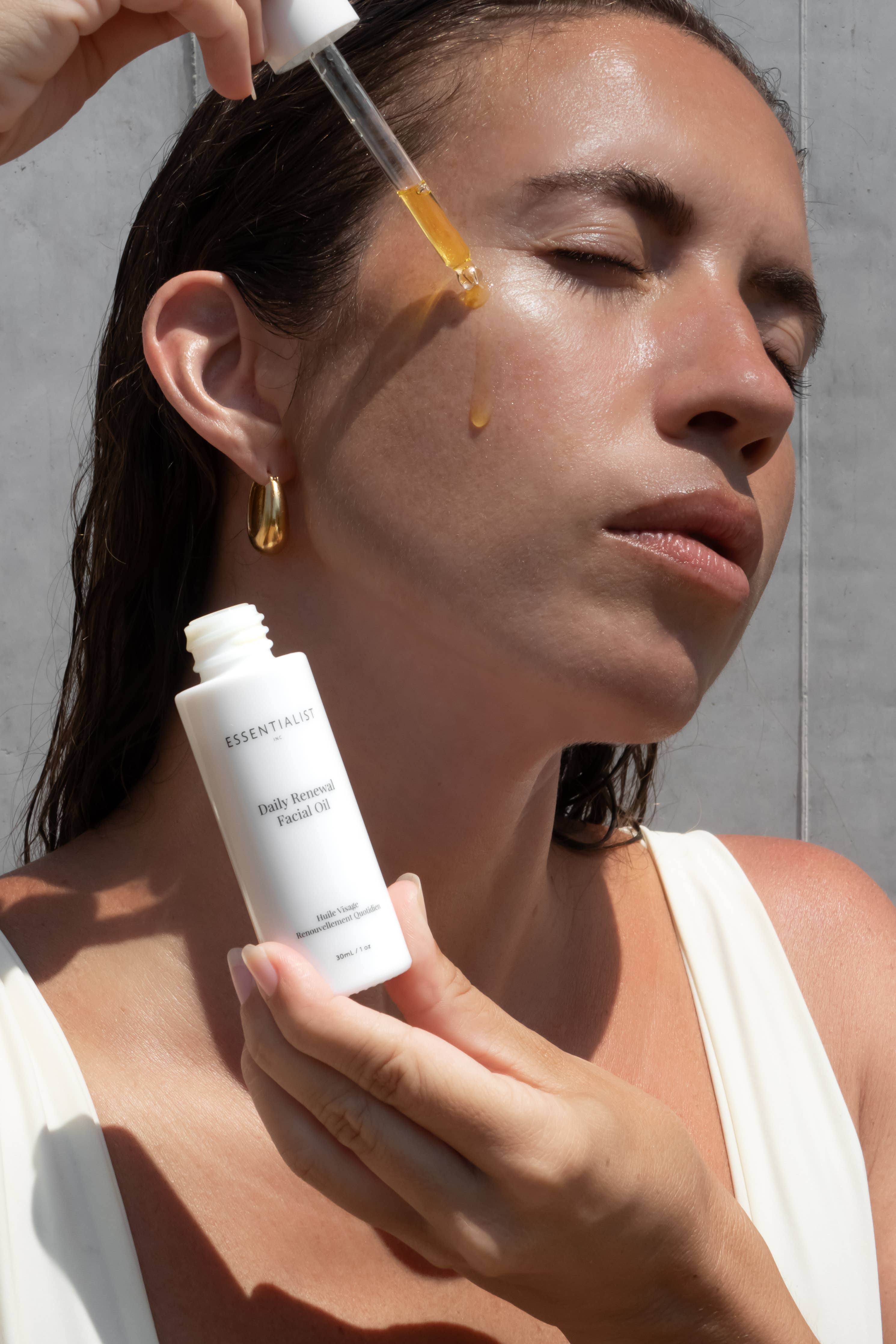 Woman applying a skincare product with a dropper to her face.