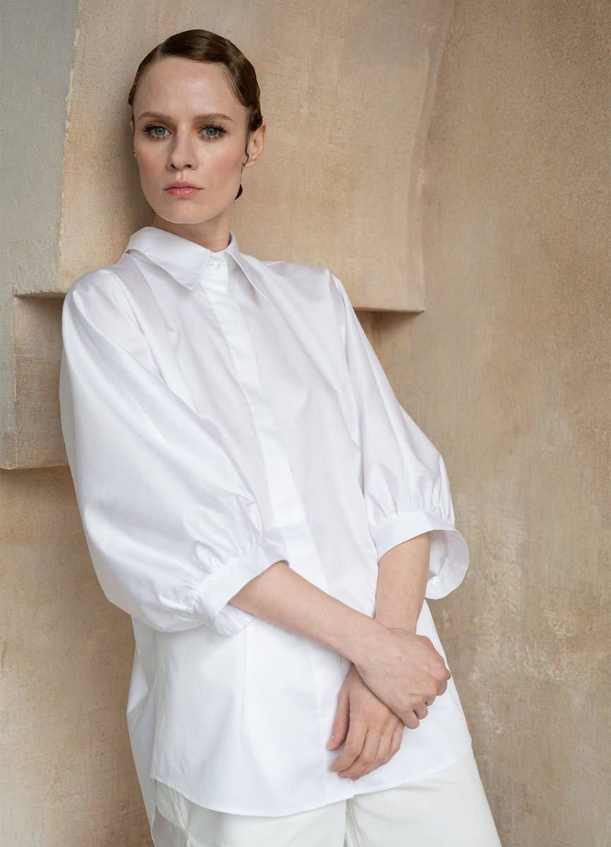 Woman wearing a white shirt against a beige wall