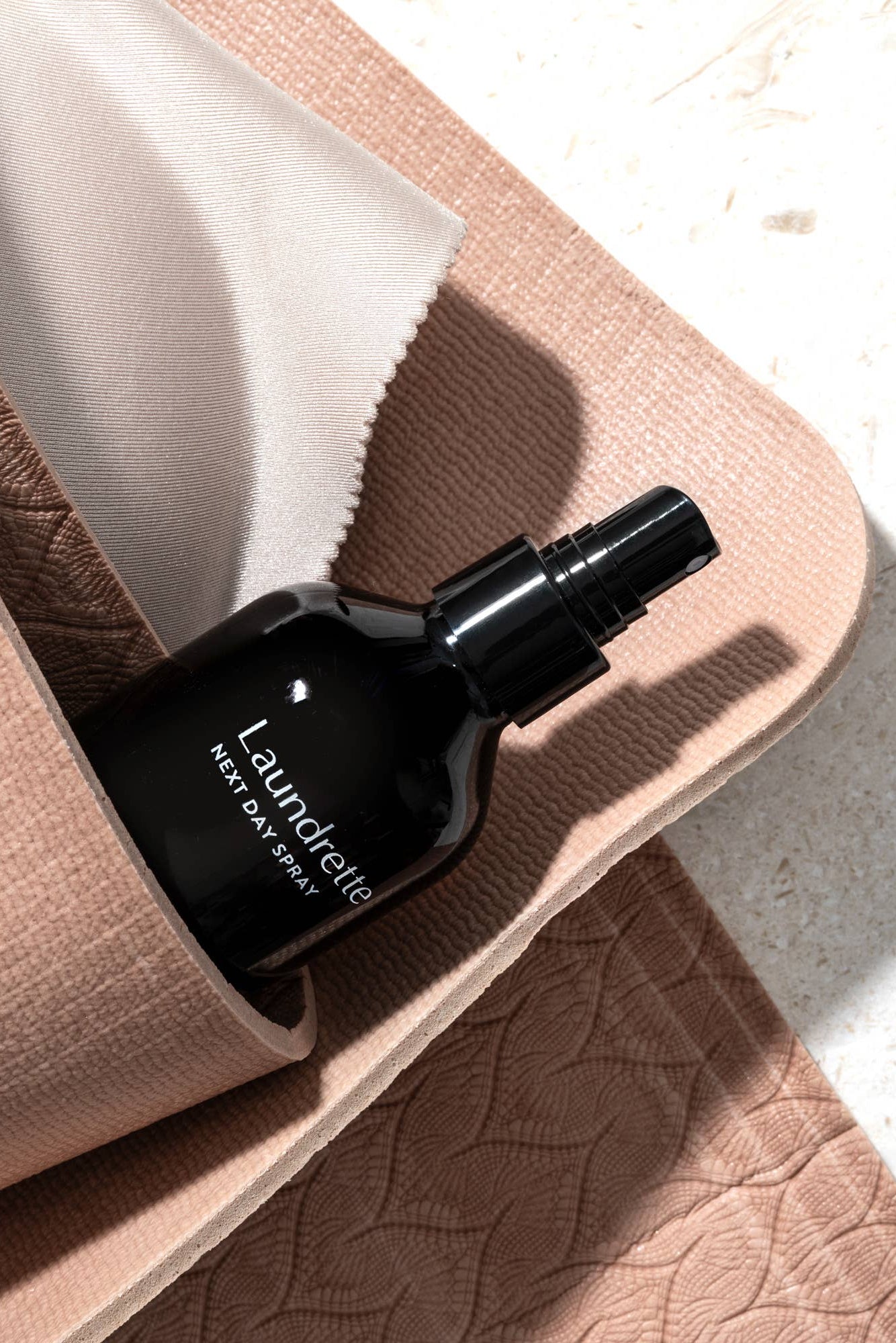 Black spray bottle labeled 'Laundrefy' on a textured surface