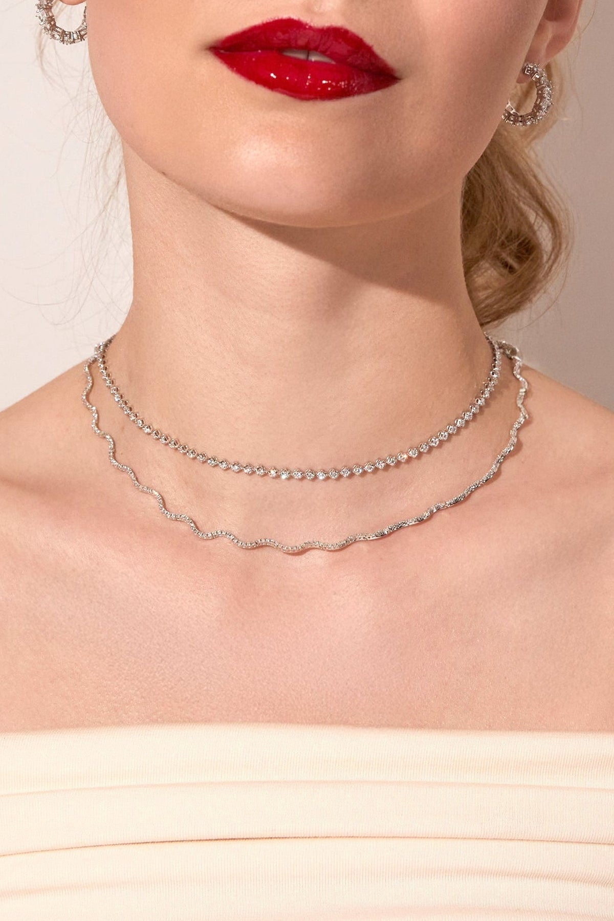Close-up of a woman wearing a silver necklace with a neutral background