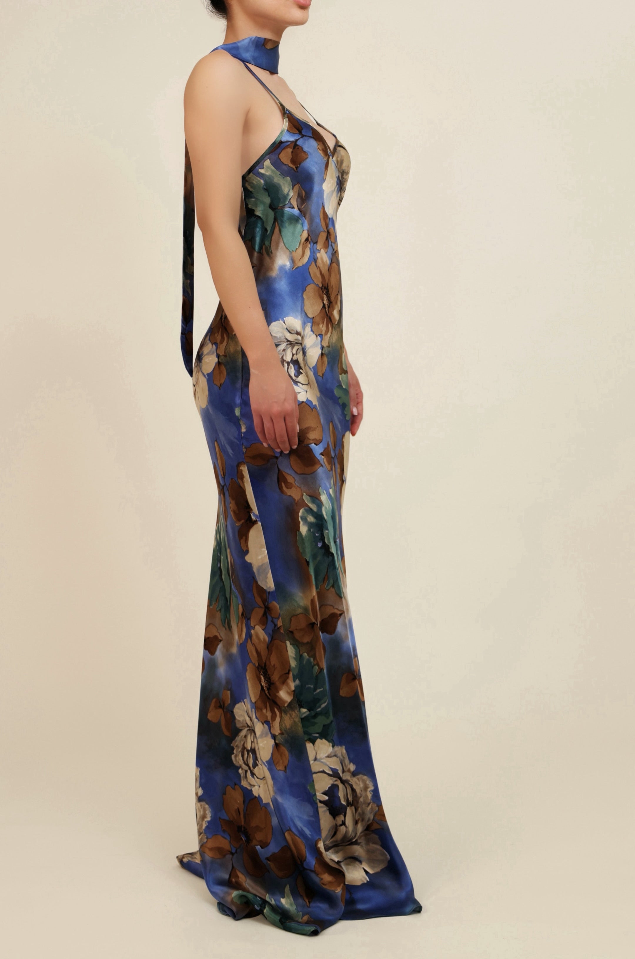 Woman wearing a floral evening gown on a beige background