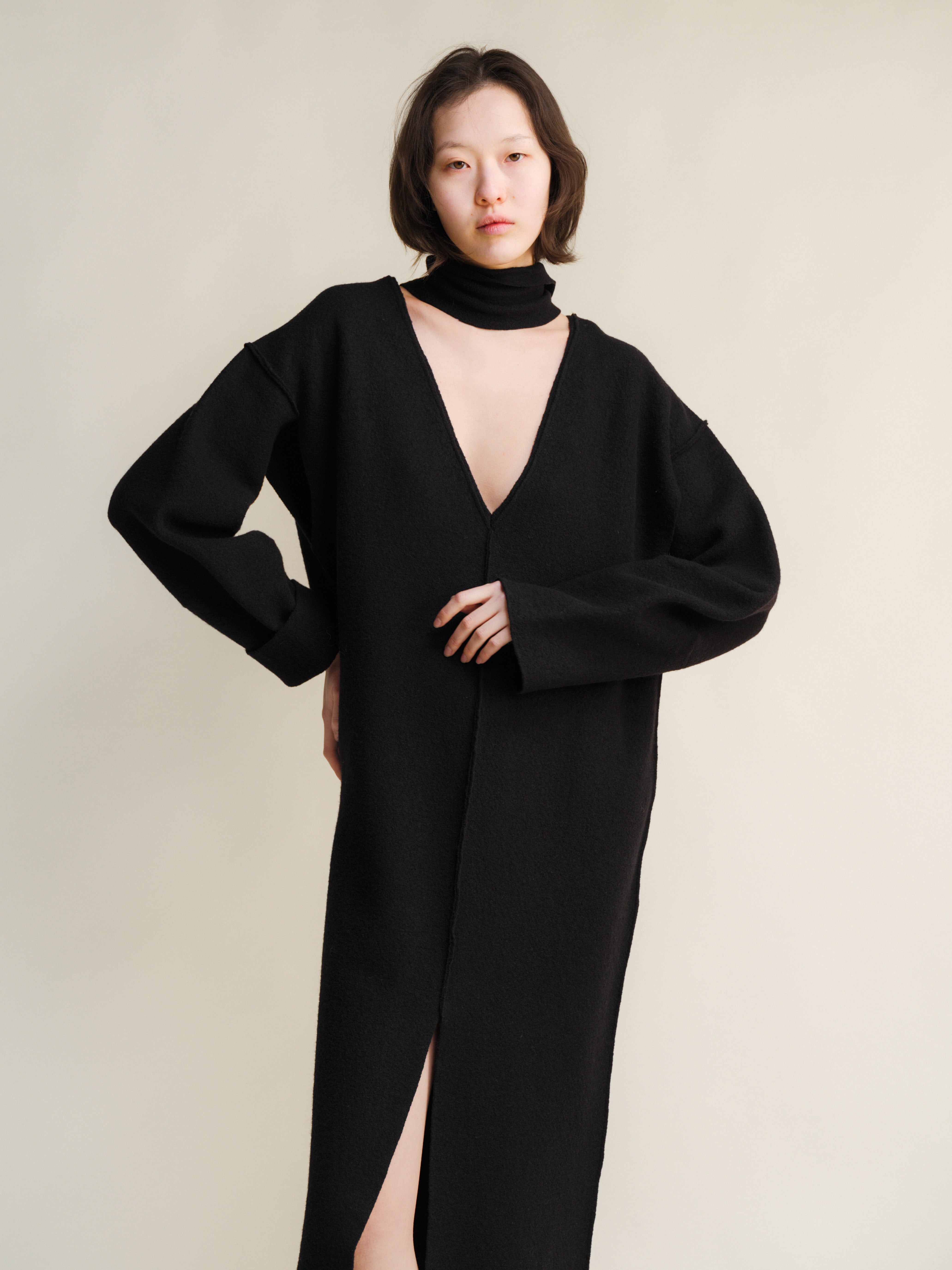 Woman wearing a black dress with a deep neckline on a plain background