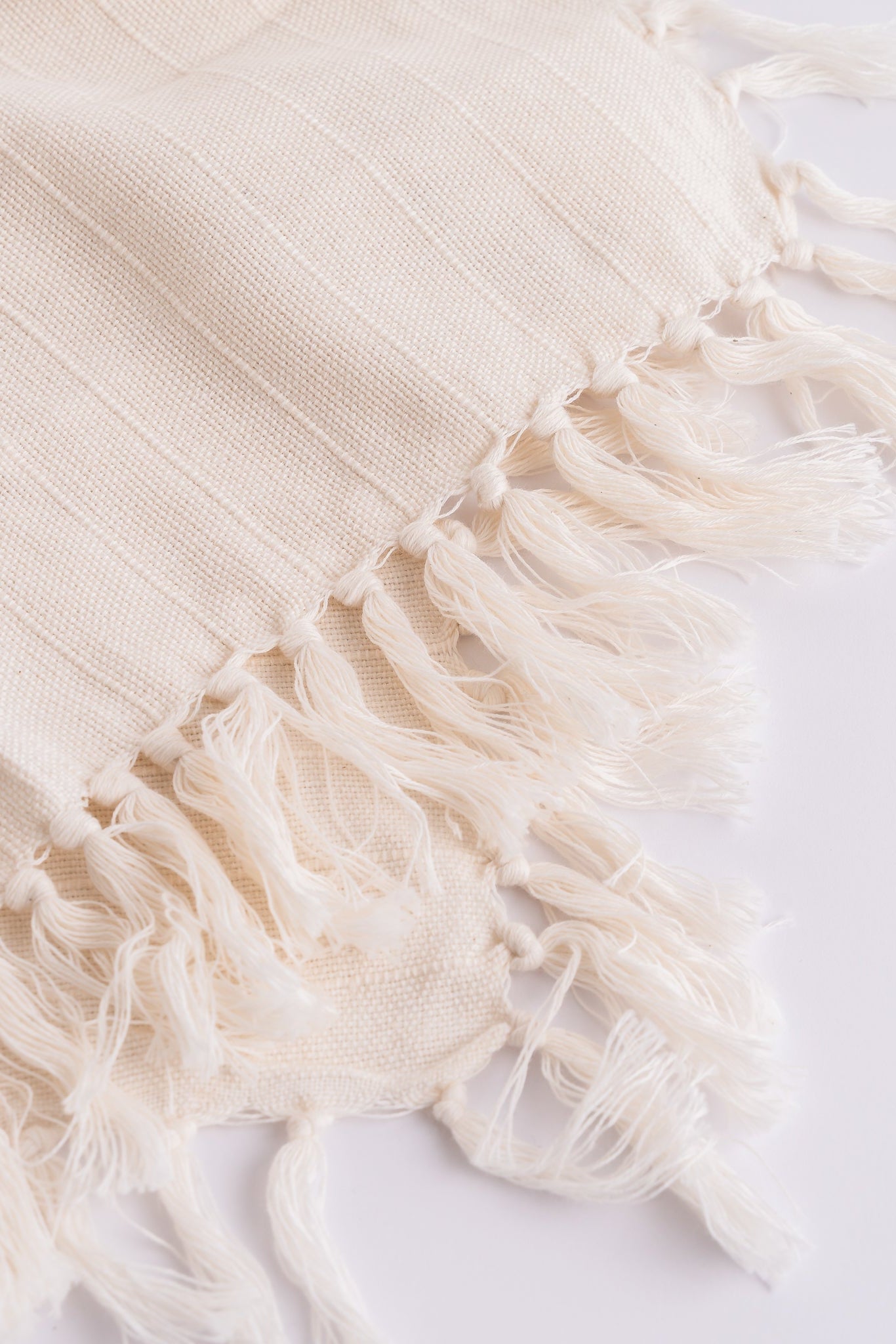 Close-up of a beige towel with fringes on a white background