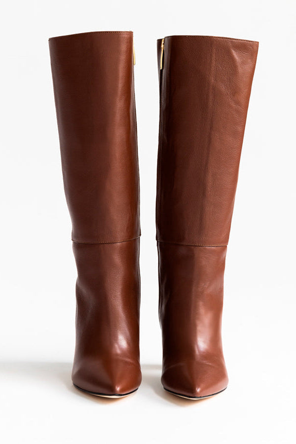 A pair of brown leather knee-high boots with pointed toes and low block heels, shown from the front on a white background.