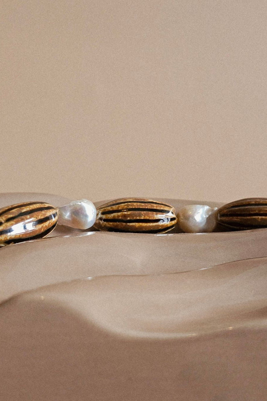 Close-up of a bracelet with pearls and gold accents on a beige background