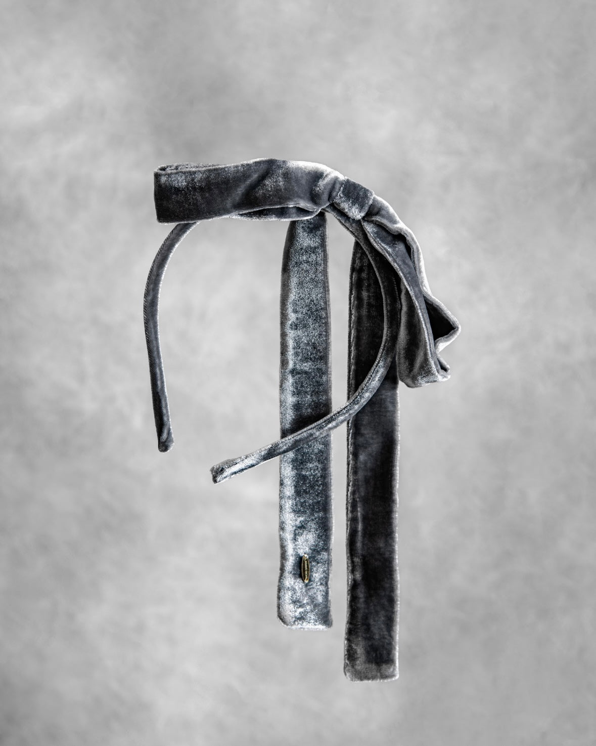 Gray velvet headband with a bow on a gray background