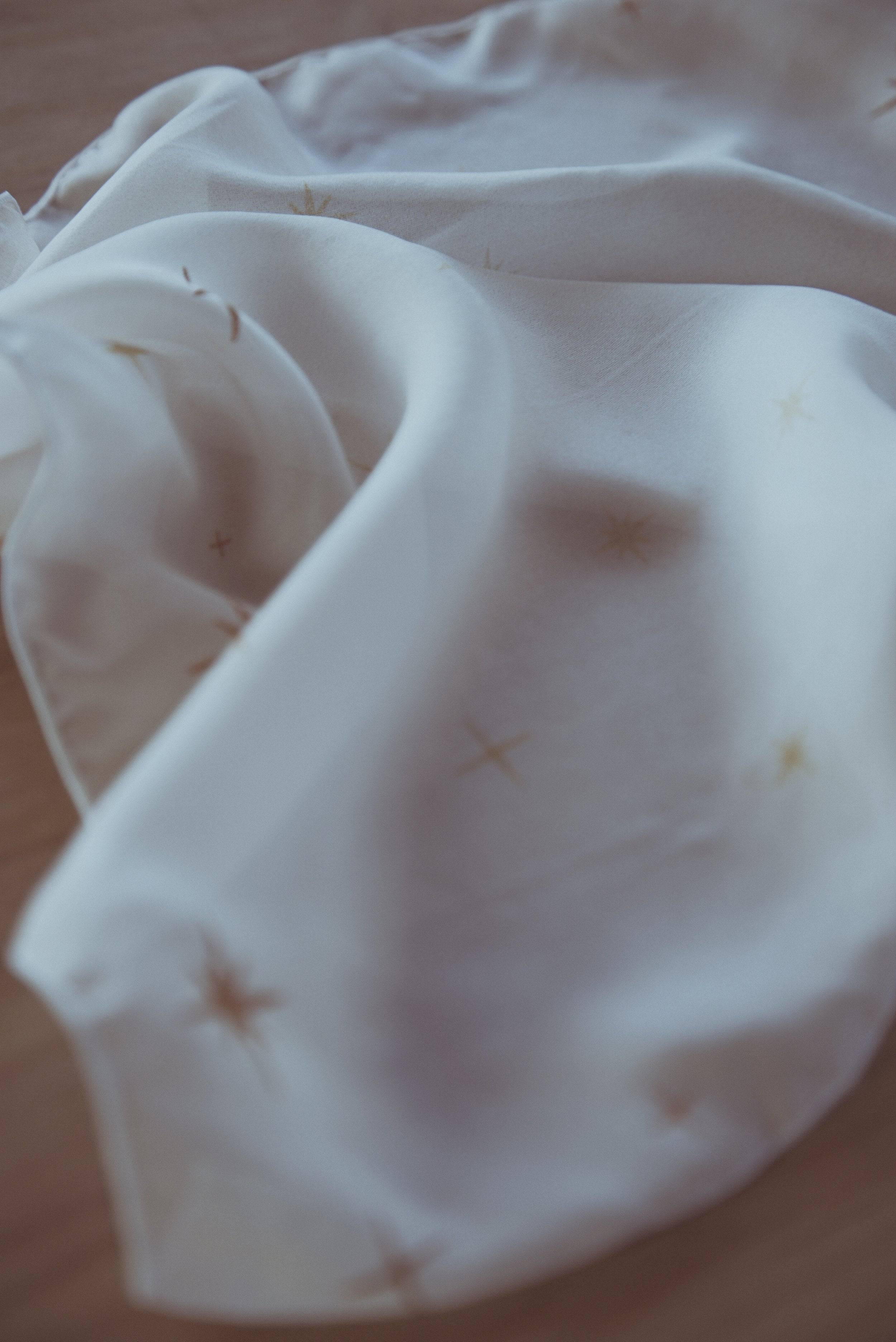 White fabric with small stains on a wooden surface