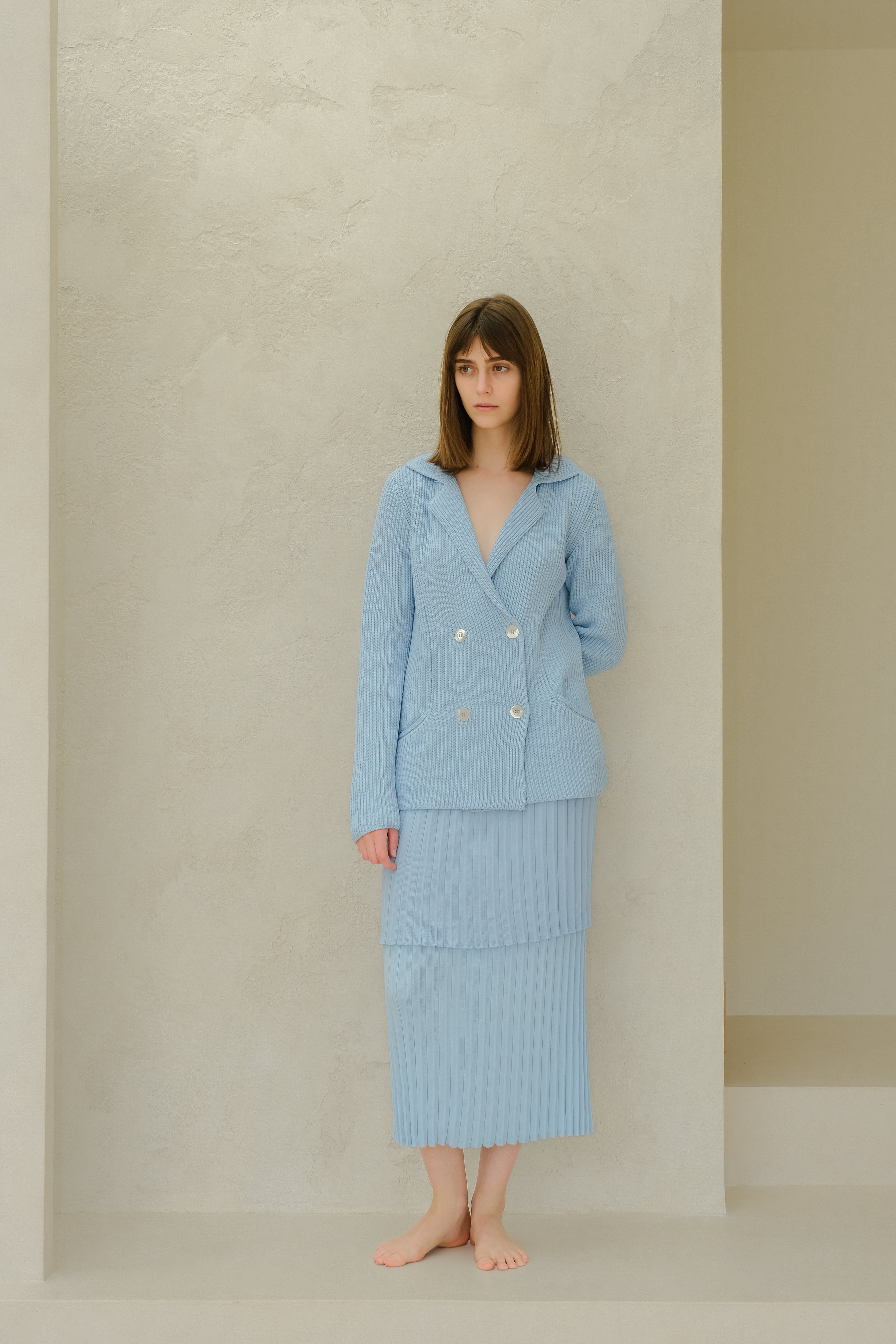 Woman wearing a light blue outfit against a neutral background