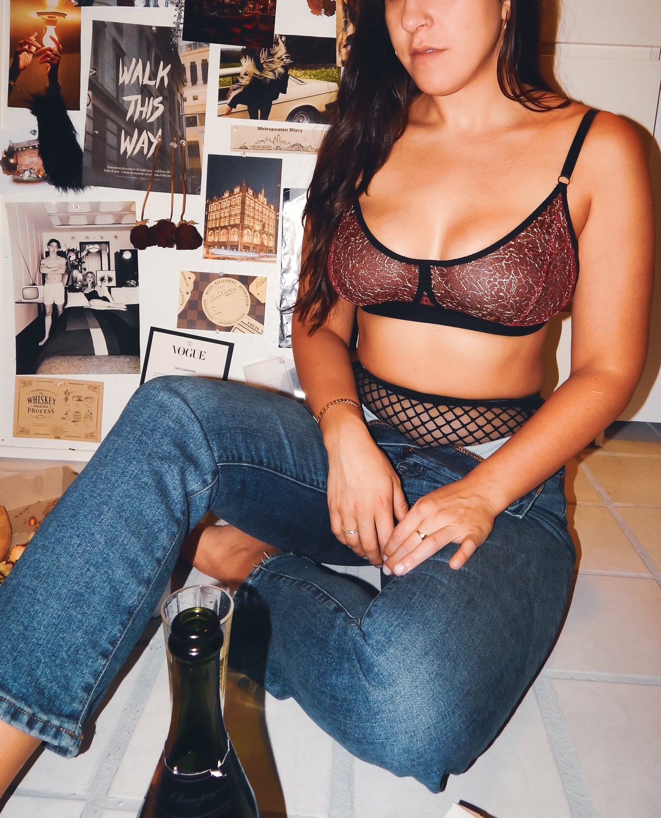 Woman wearing a black lace bralette and fishnet stockings sitting in front of a collage of images.