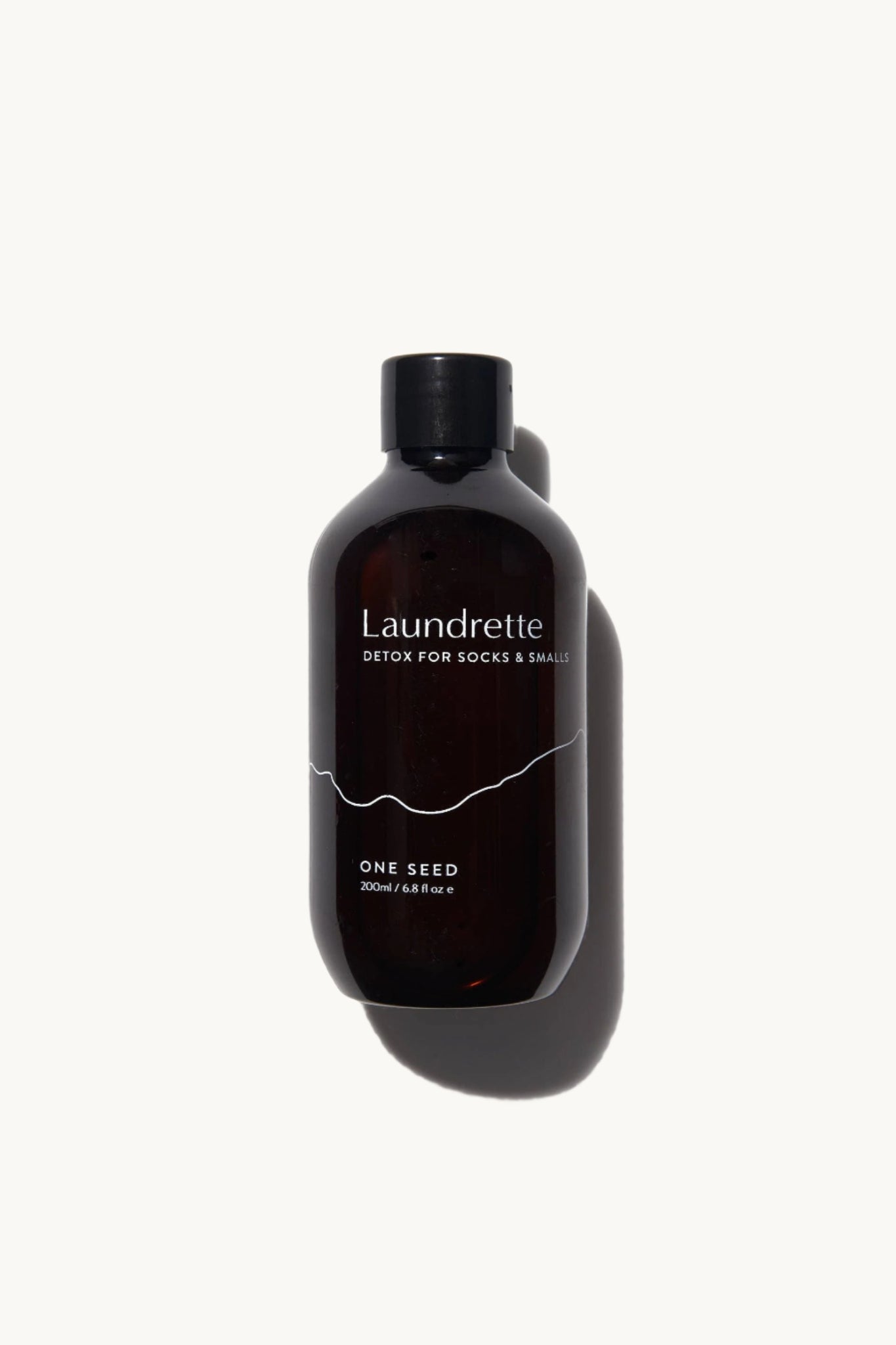 A bottle of Laundrette brand Detox for Socks & Smalls with a dark label and orange blossom fragrance, designed for sanitizing delicate items.