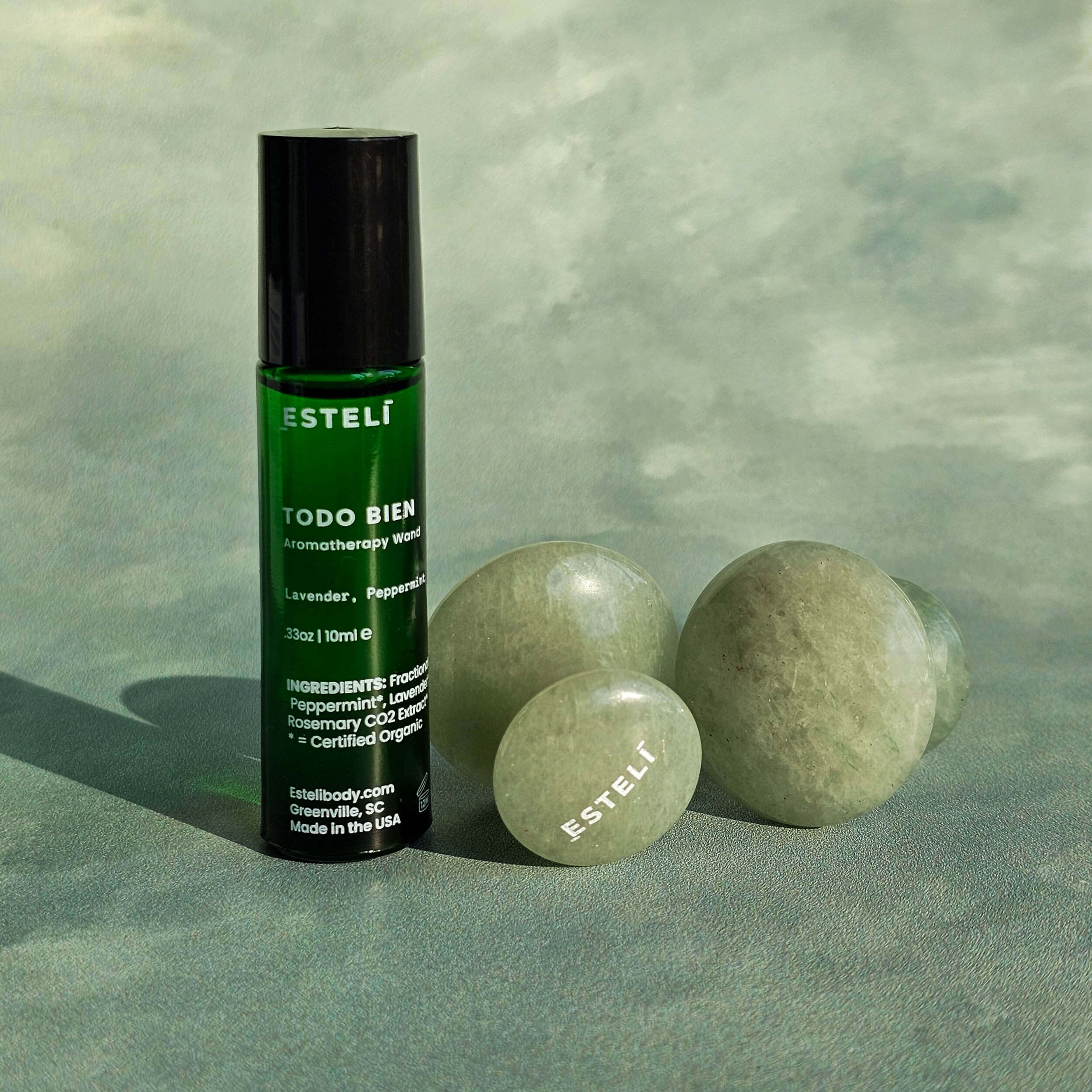 EstéliTODO BIEN aromatherapy roller bottle with green stones on a textured green background