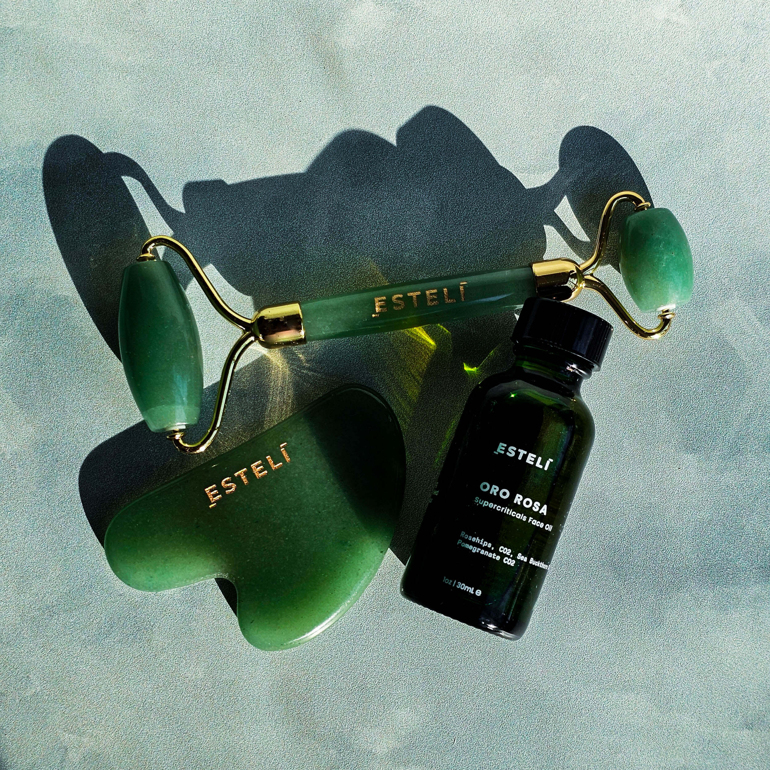 Estelt jade roller and bottle on a textured light blue background