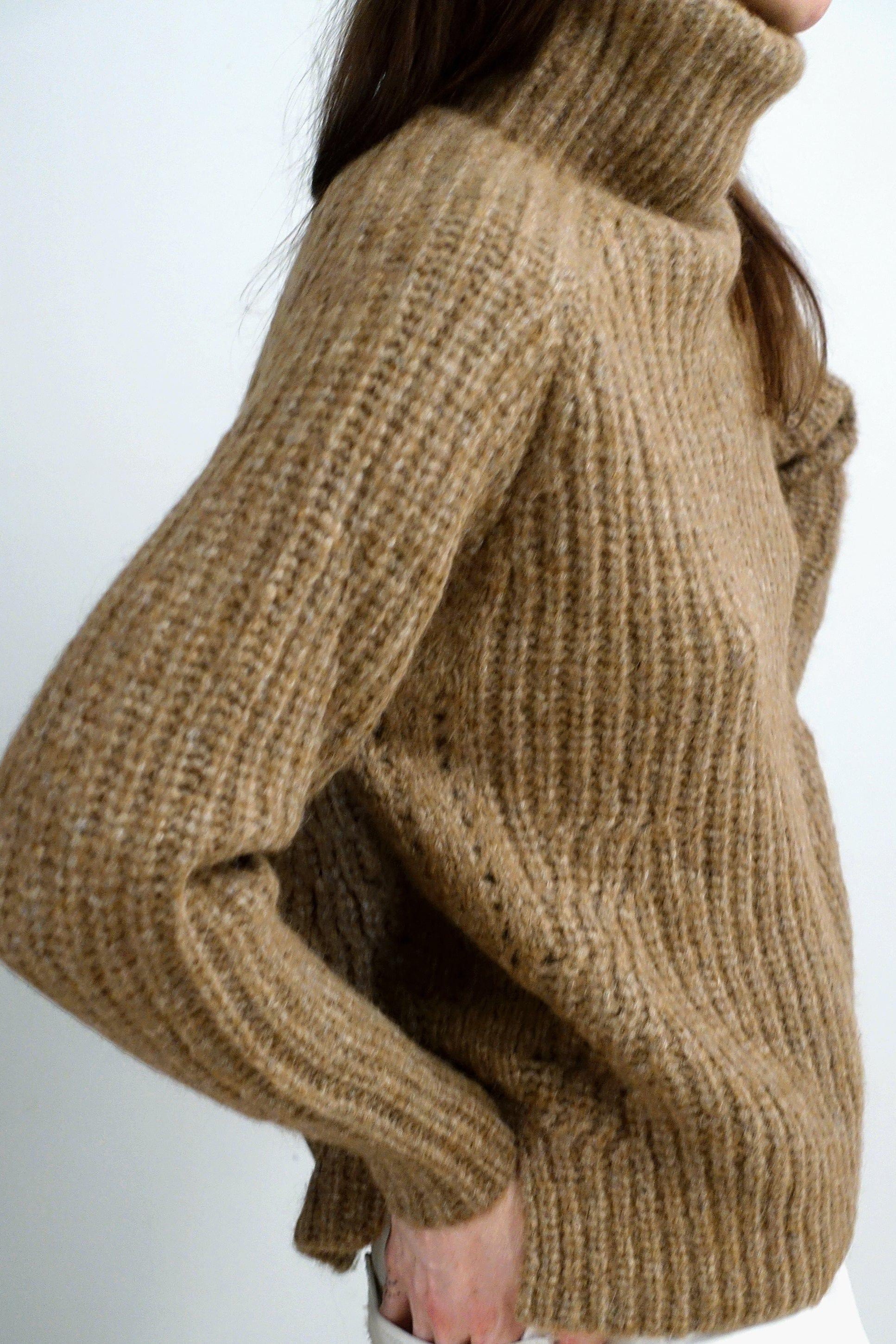Close-up of a person wearing a brown turtleneck sweater against a white background