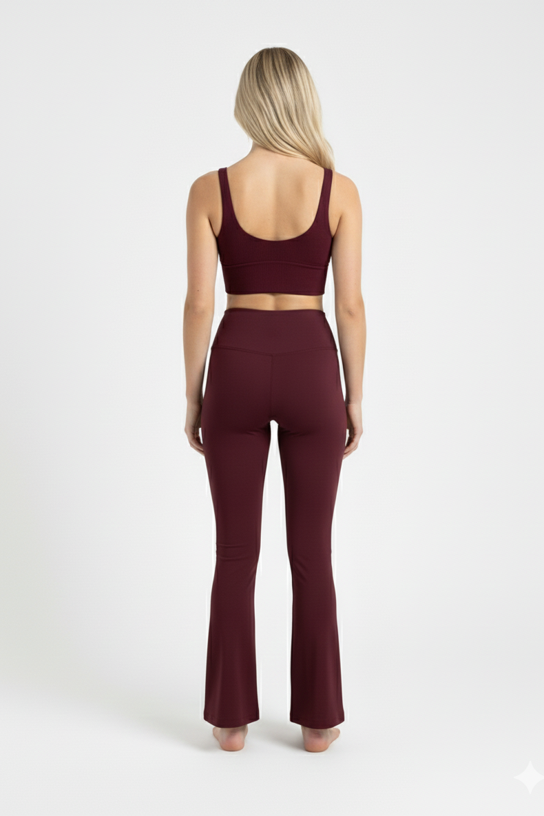 Woman wearing a burgundy sports bra and leggings set on a white background