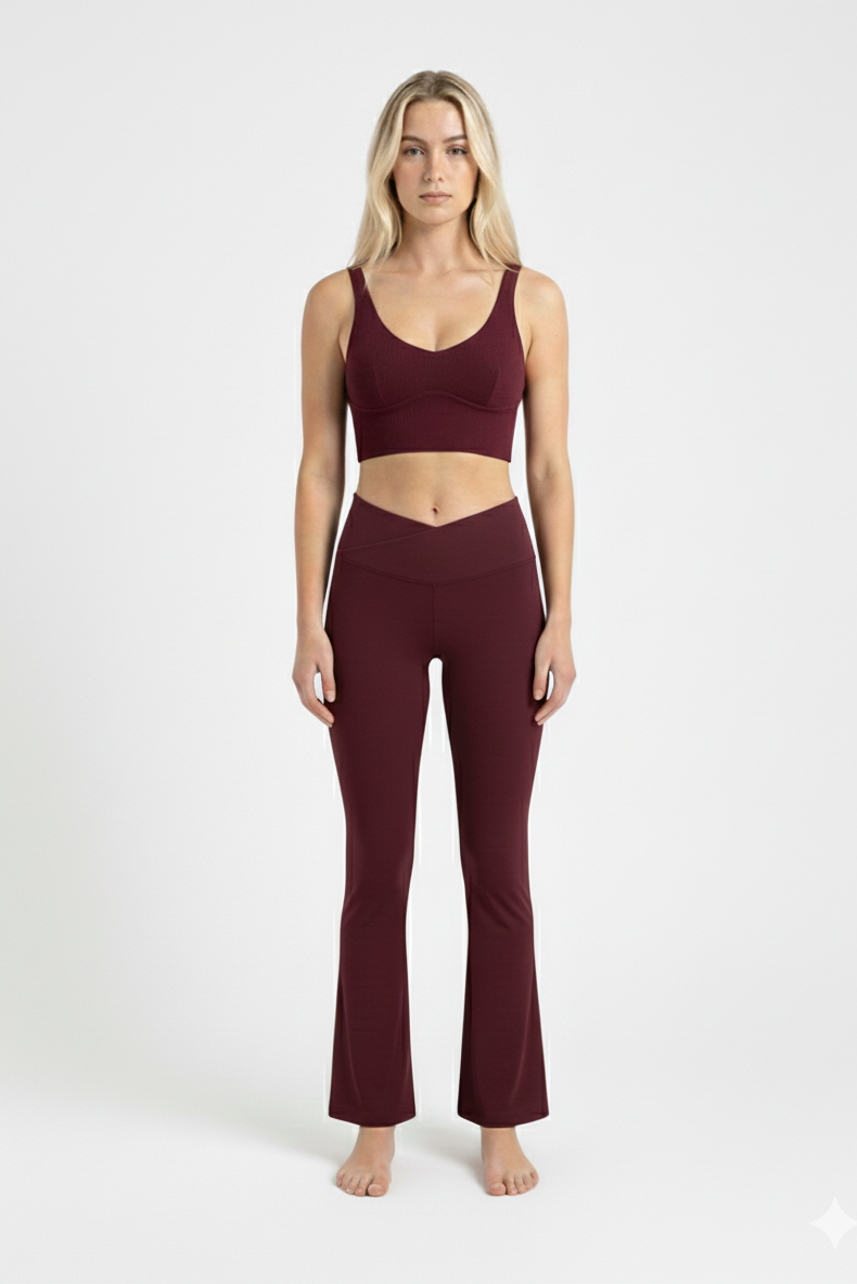 Woman wearing a burgundy sports bra and leggings on a white background