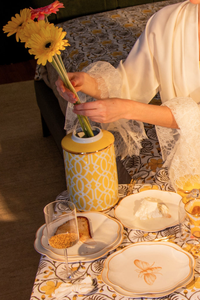 Person arranging flowers at a table with decorative plates and glasses.