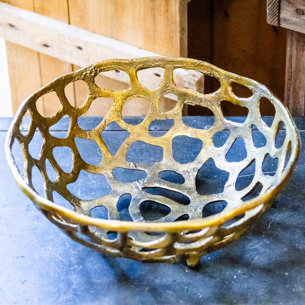 Decorative metal bowl with a lattice design on a blue surface.