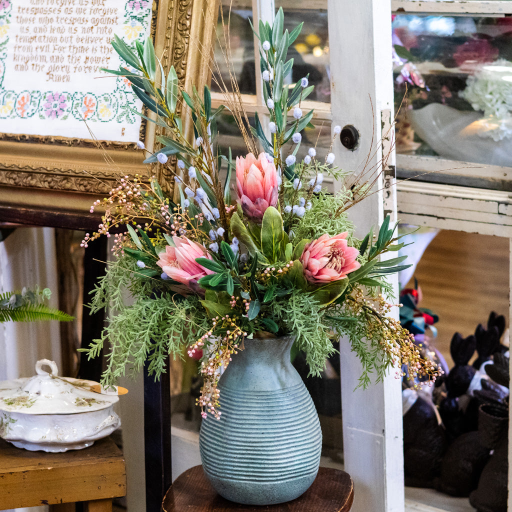 Decorative floral arrangement in a textured blue vase on a wooden surface.