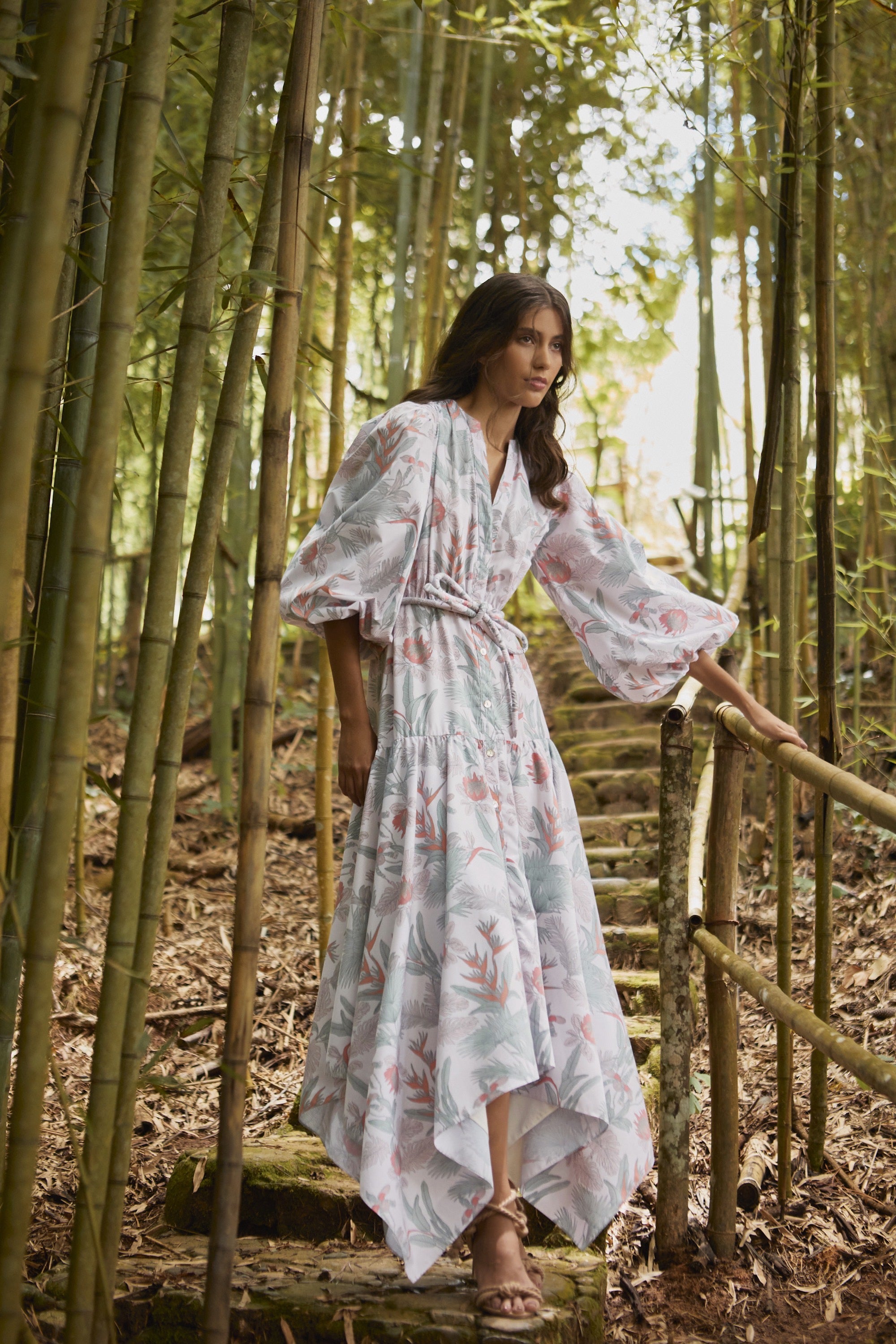 Woman in a floral dress standing in a forest with bamboo