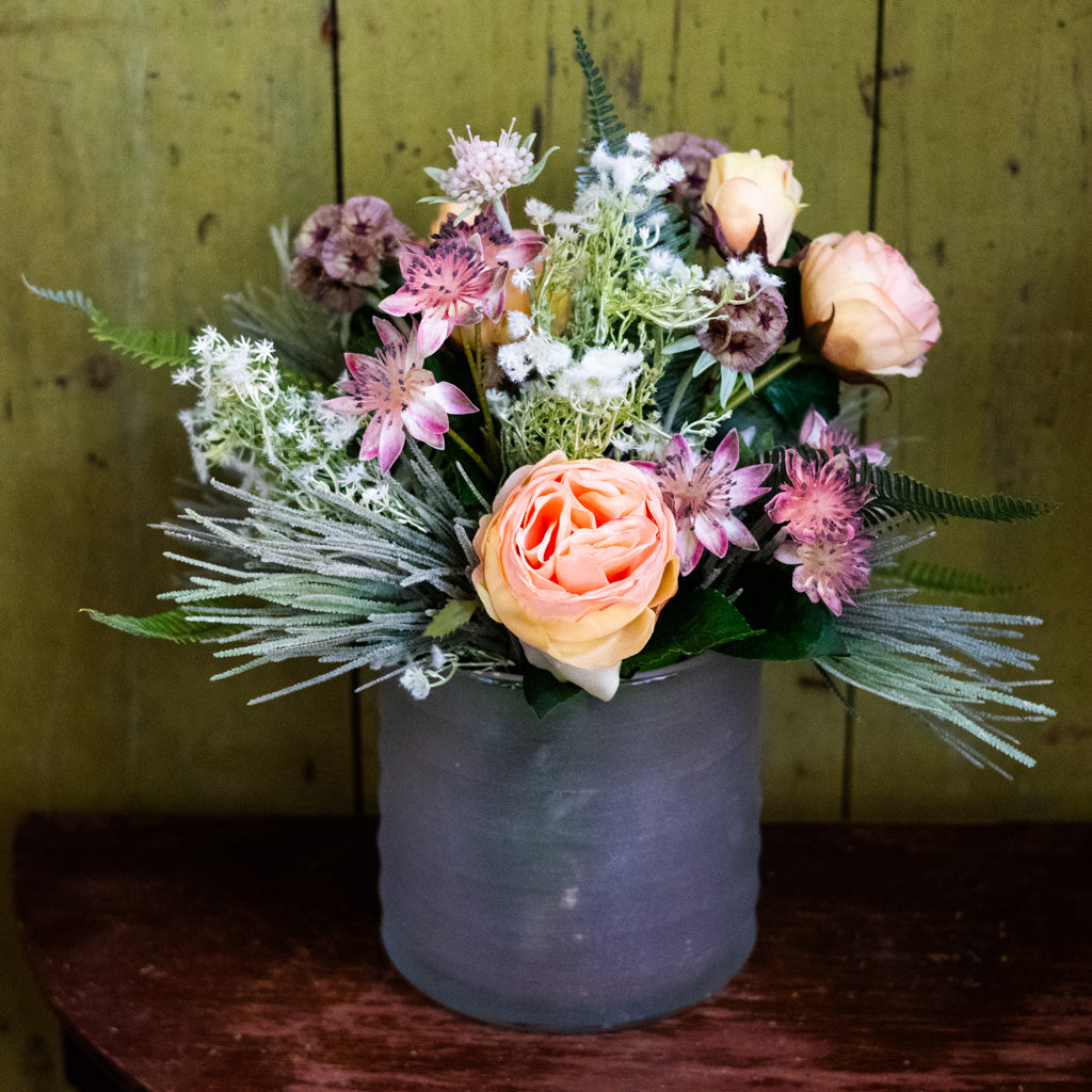 Bouquet of flowers in a gray vase against a wooden background