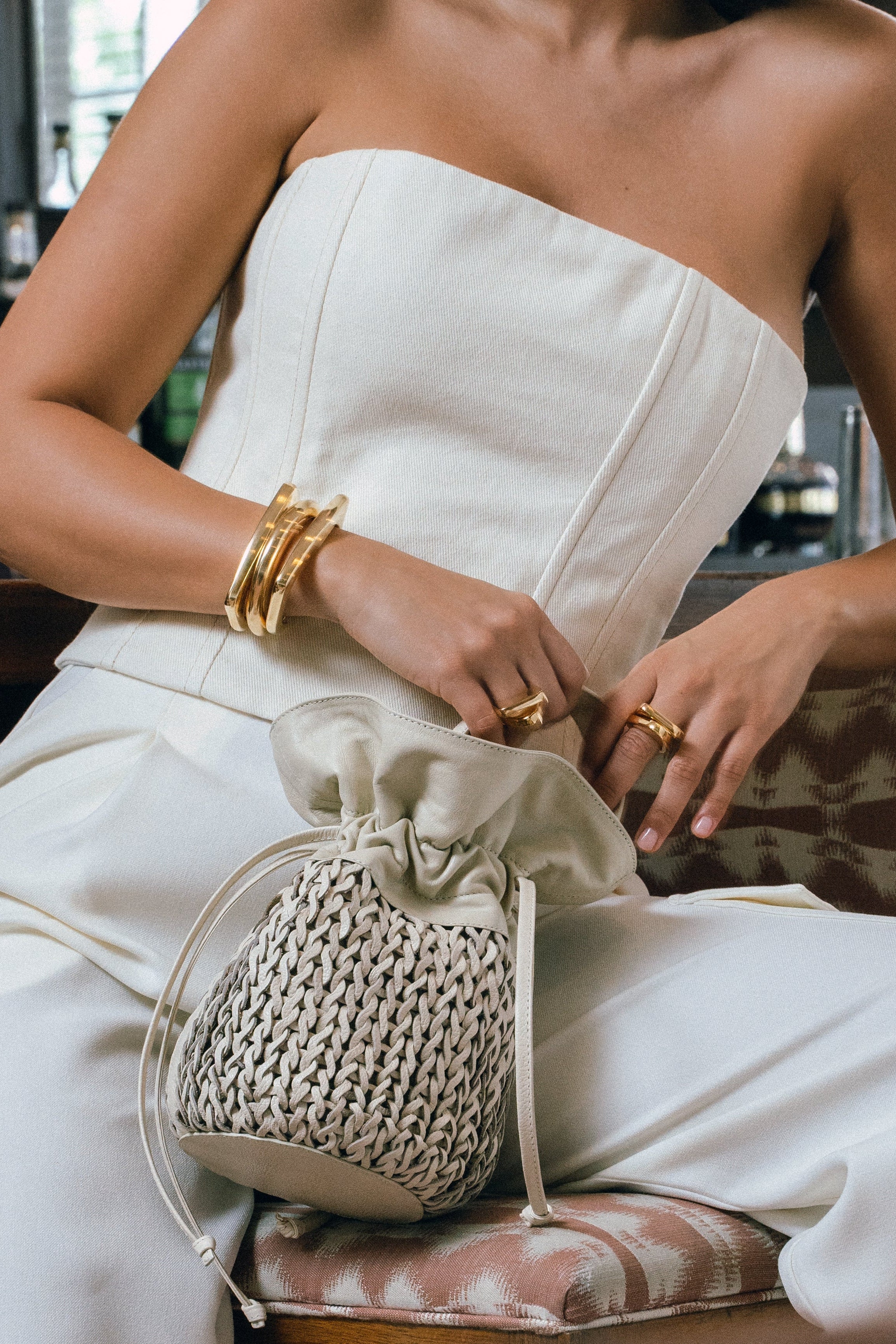 Woman in a strapless white dress holding a textured handbag.