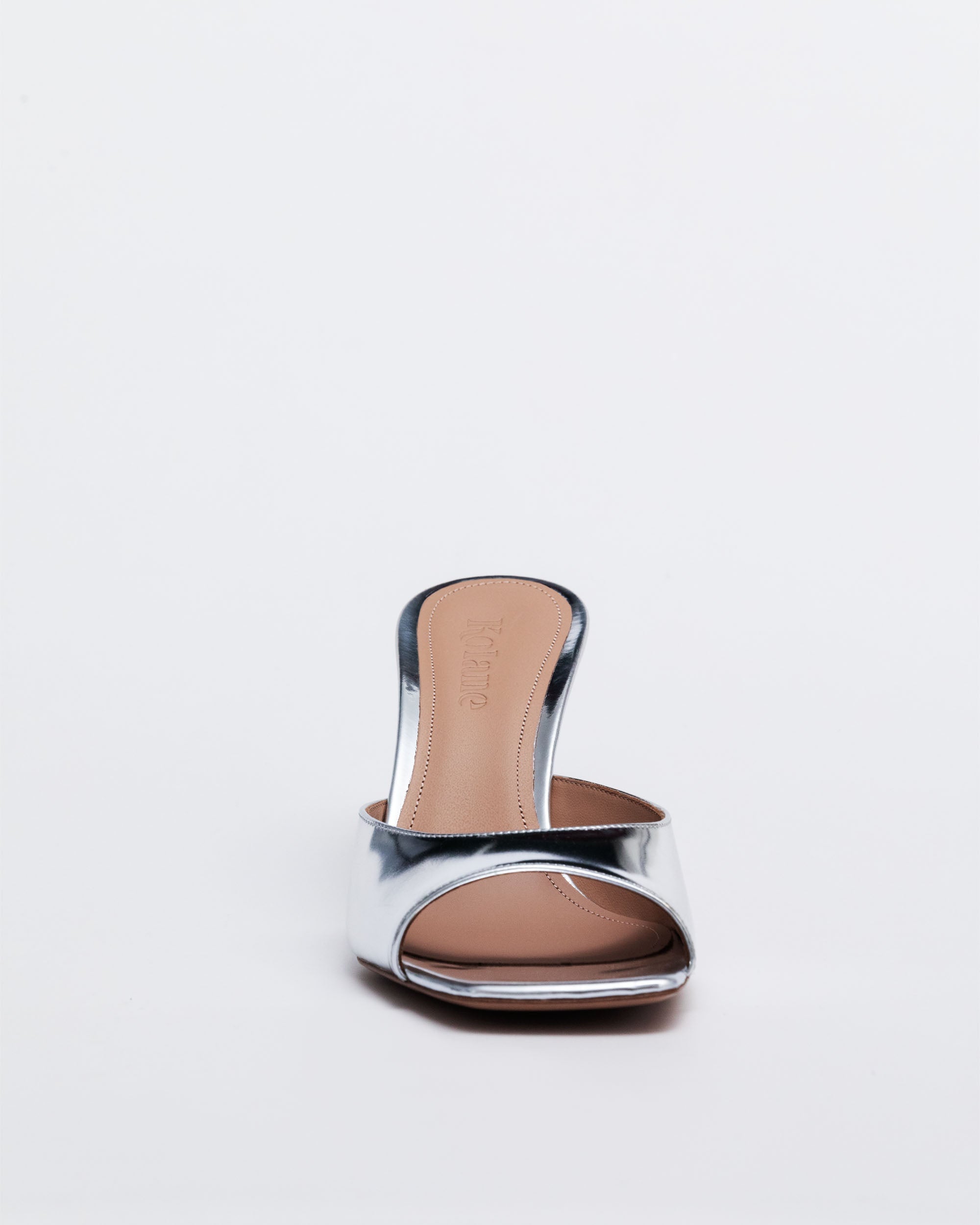 Silver high-heeled sandal with a brown sole on a light gray background
