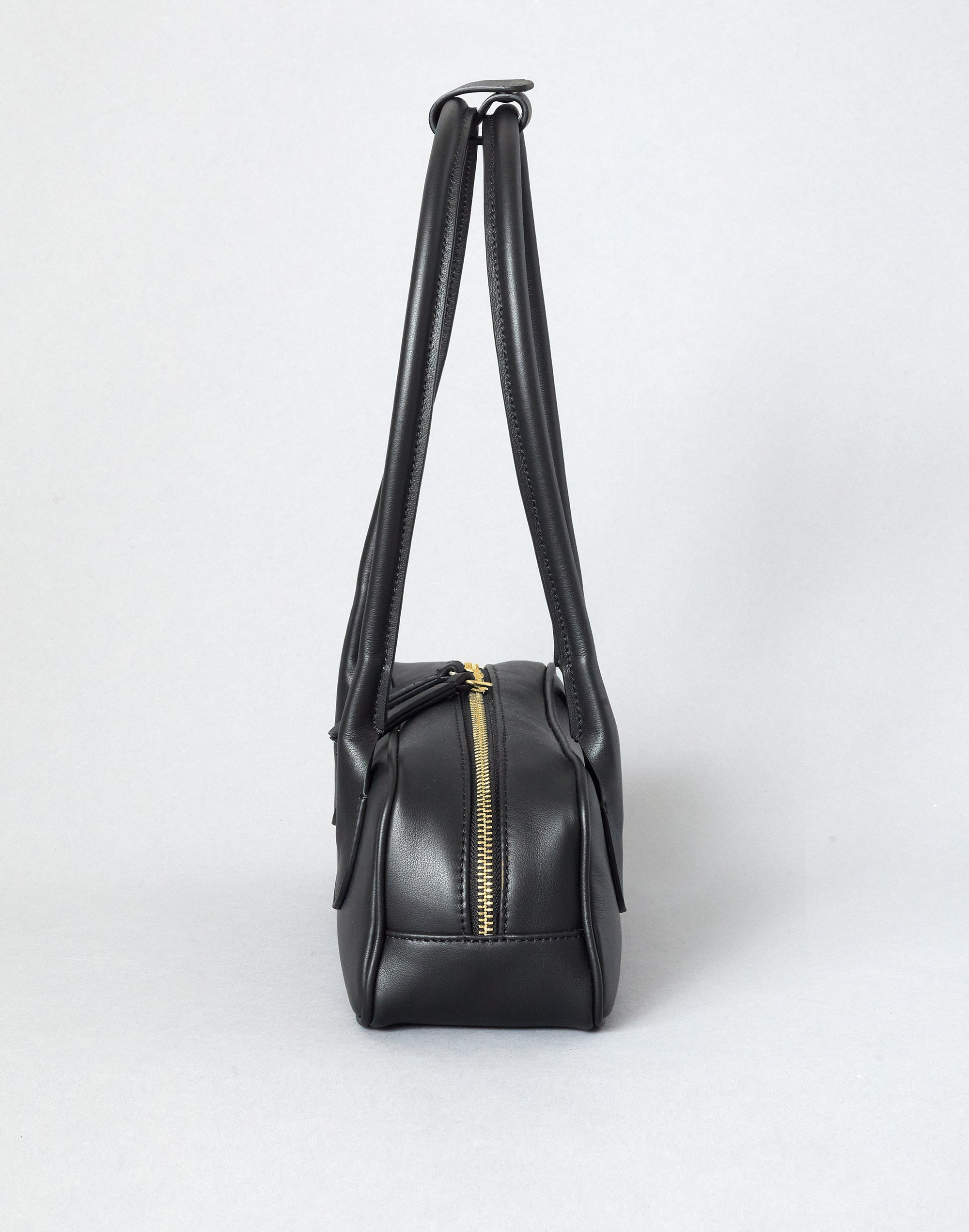 Black leather handbag with a gold zipper on a white background