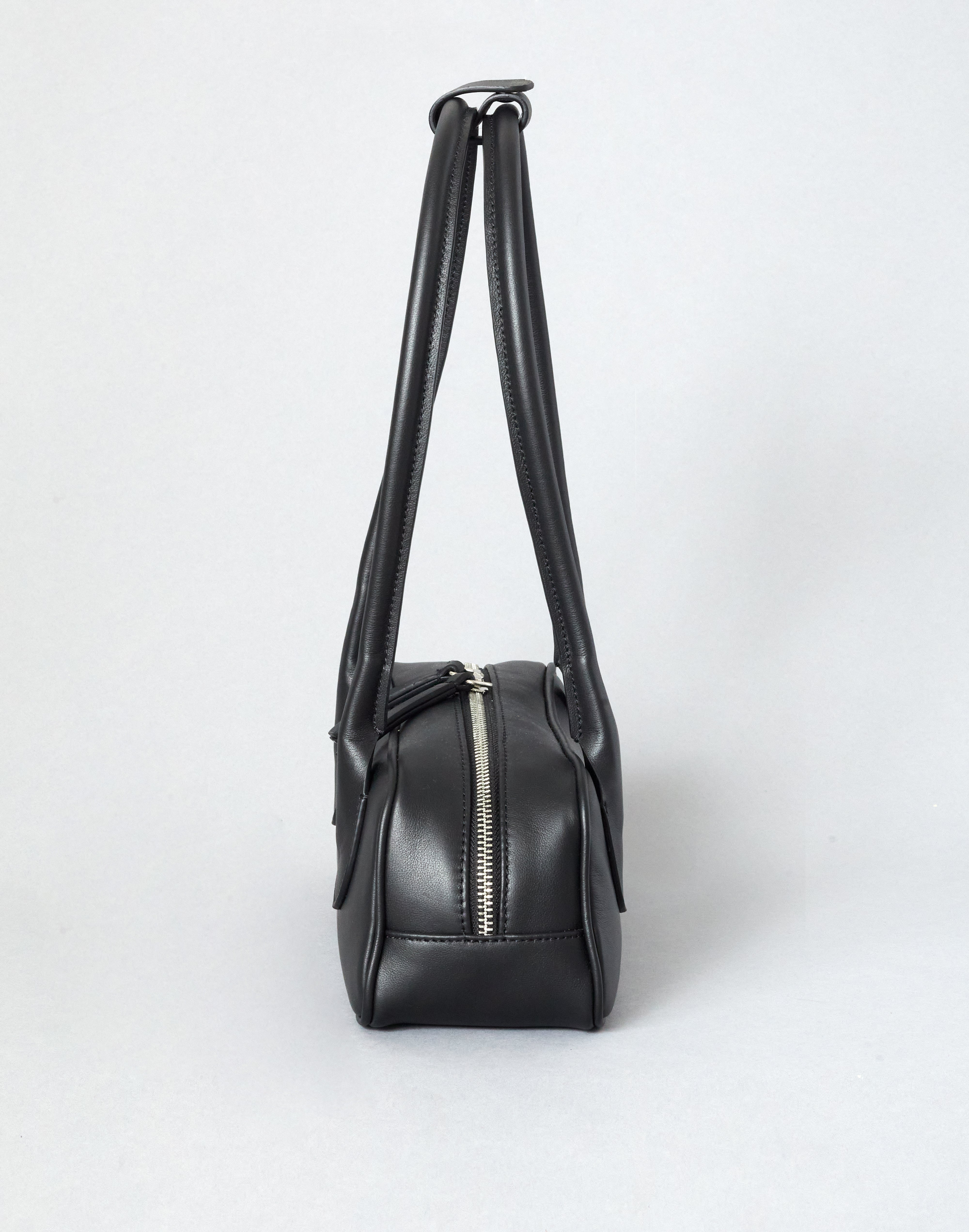 Black leather handbag with a shoulder strap on a white background