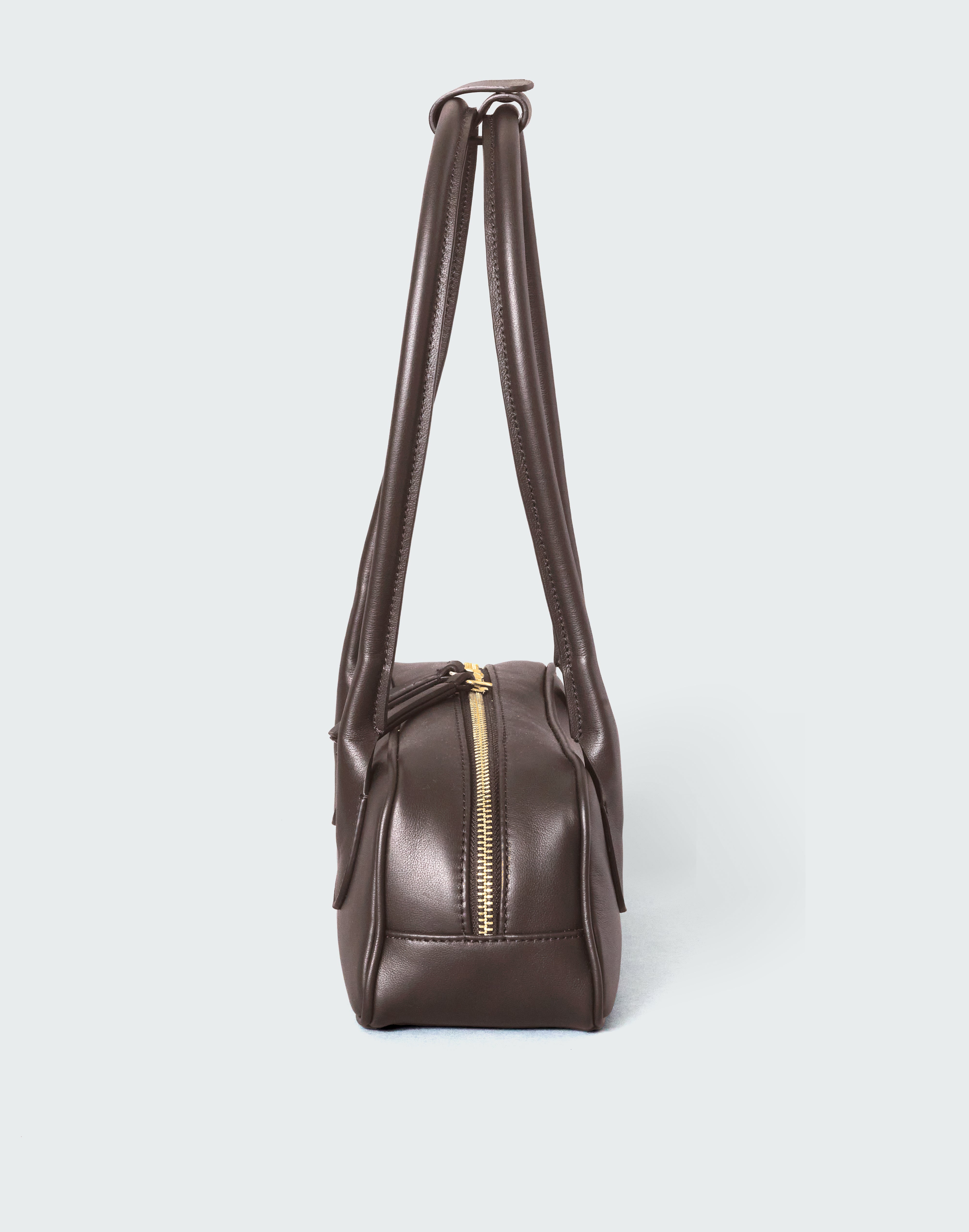 Brown leather handbag with a gold zipper on a white background