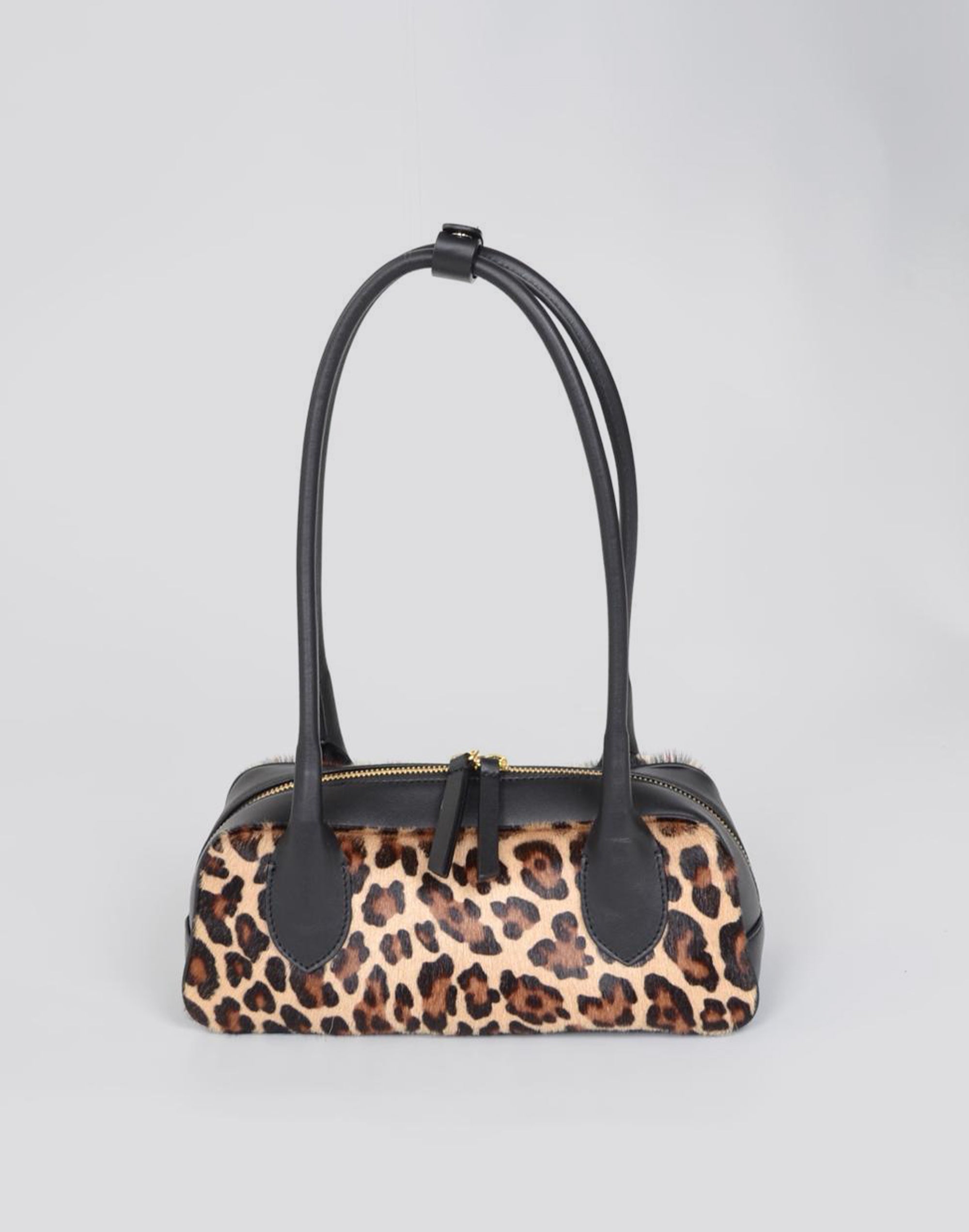 Leopard print handbag with black handle on a light gray background
