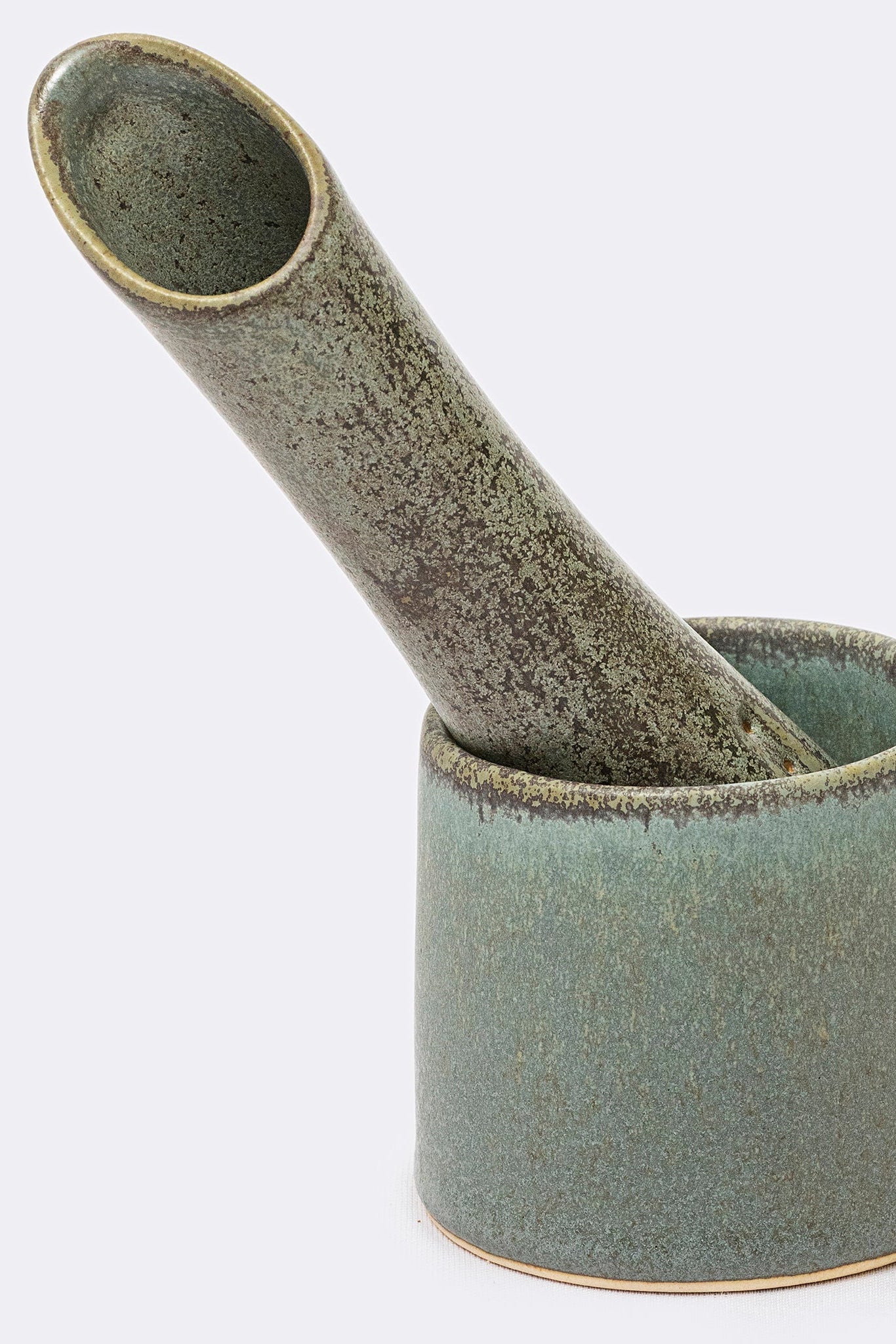Green ceramic mortar and pestle on a white background