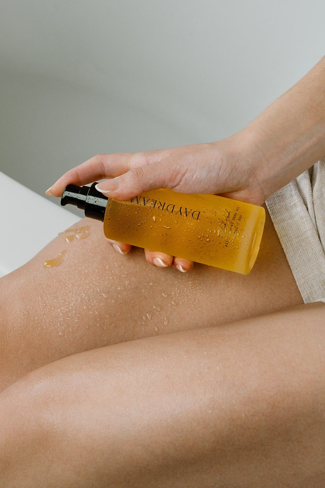Person applying a yellow bottle of body wash to their leg.