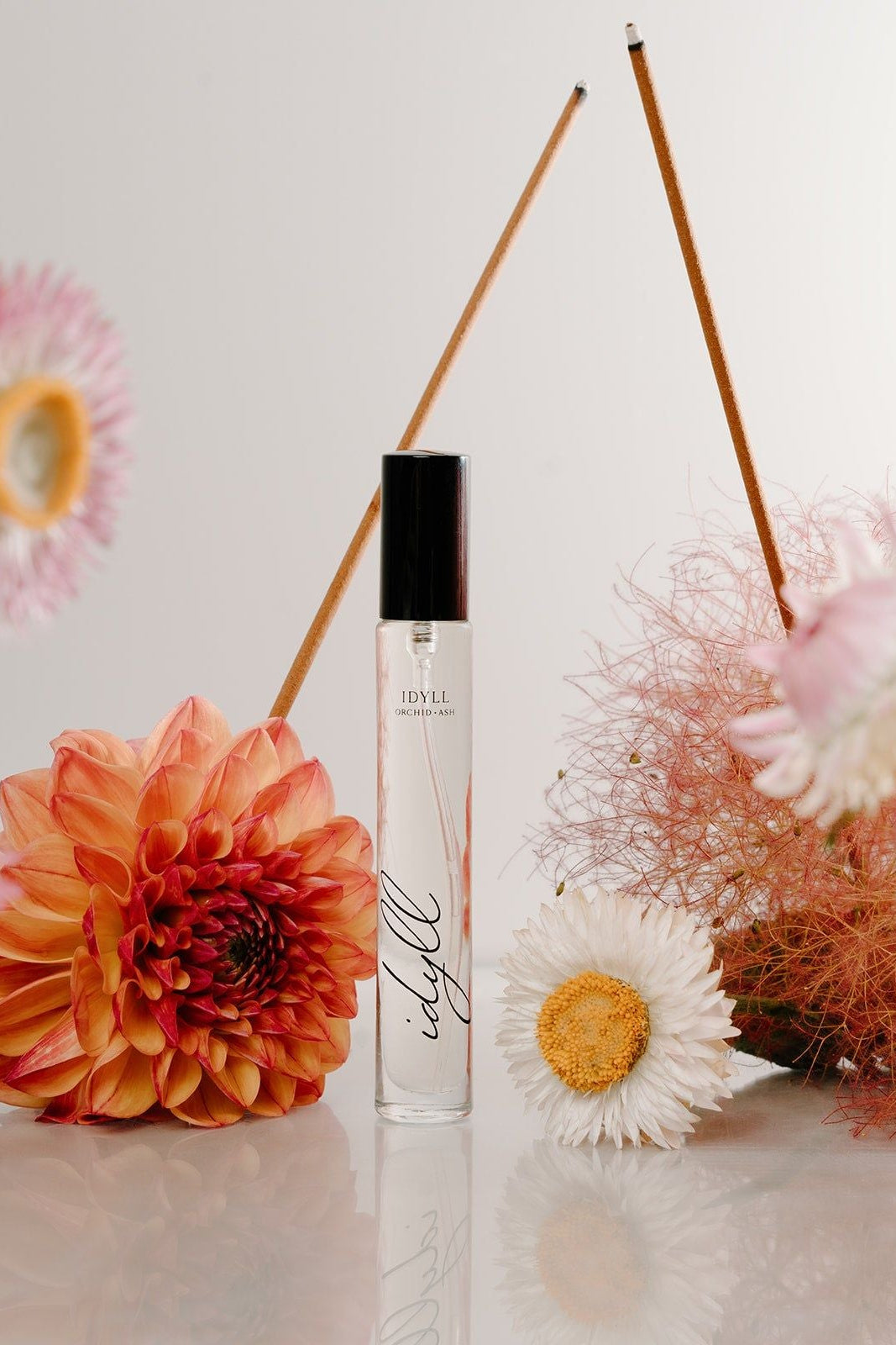 Perfume bottle with floral arrangement on a light background